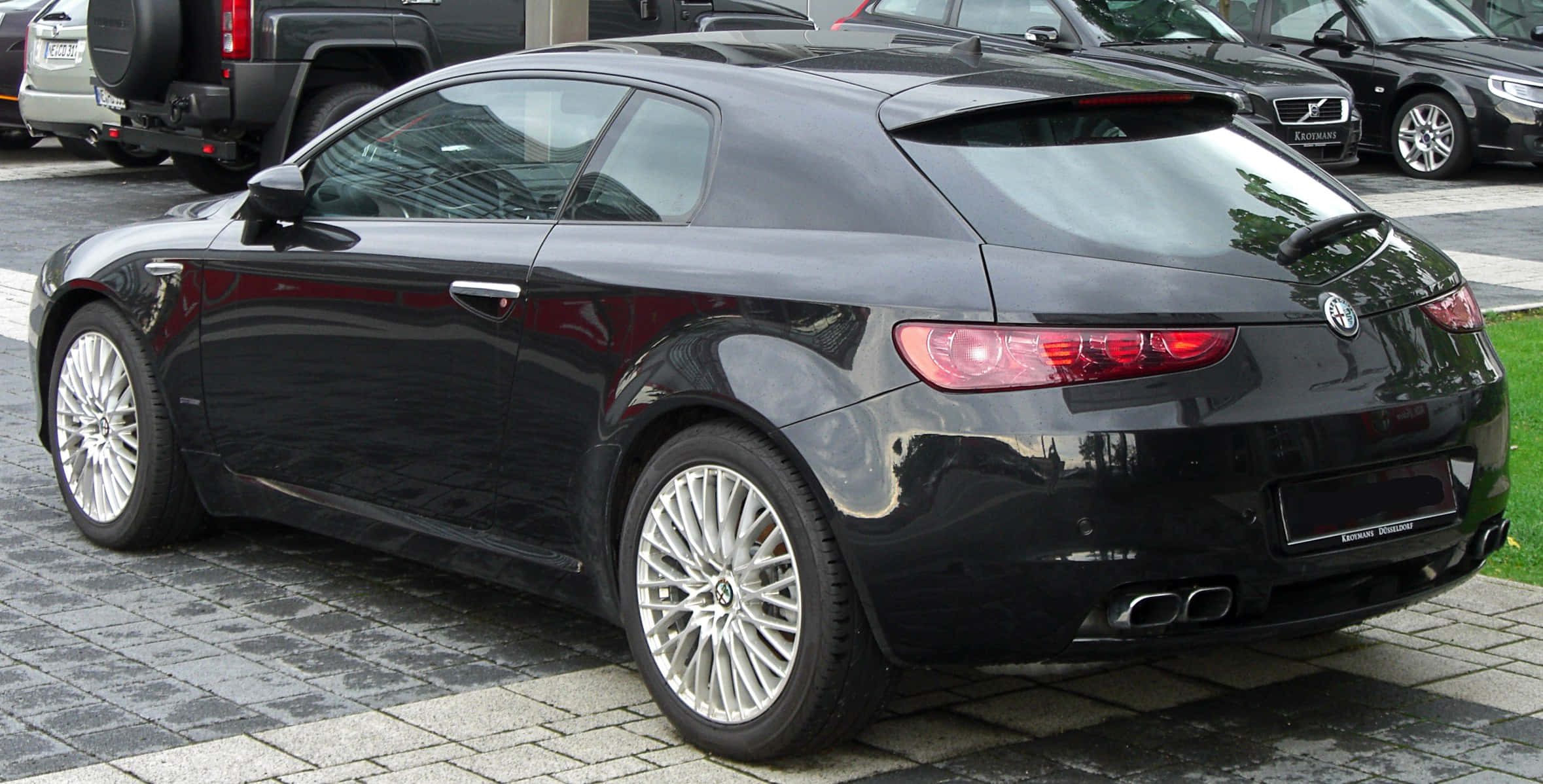 Alfa Romeo Brera 桌布 壁紙 — 一架時尚的黑色愛快羅密歐跑車雙門轎跑車停放在鋪砌的停車場上，背景可見其他車輛。
