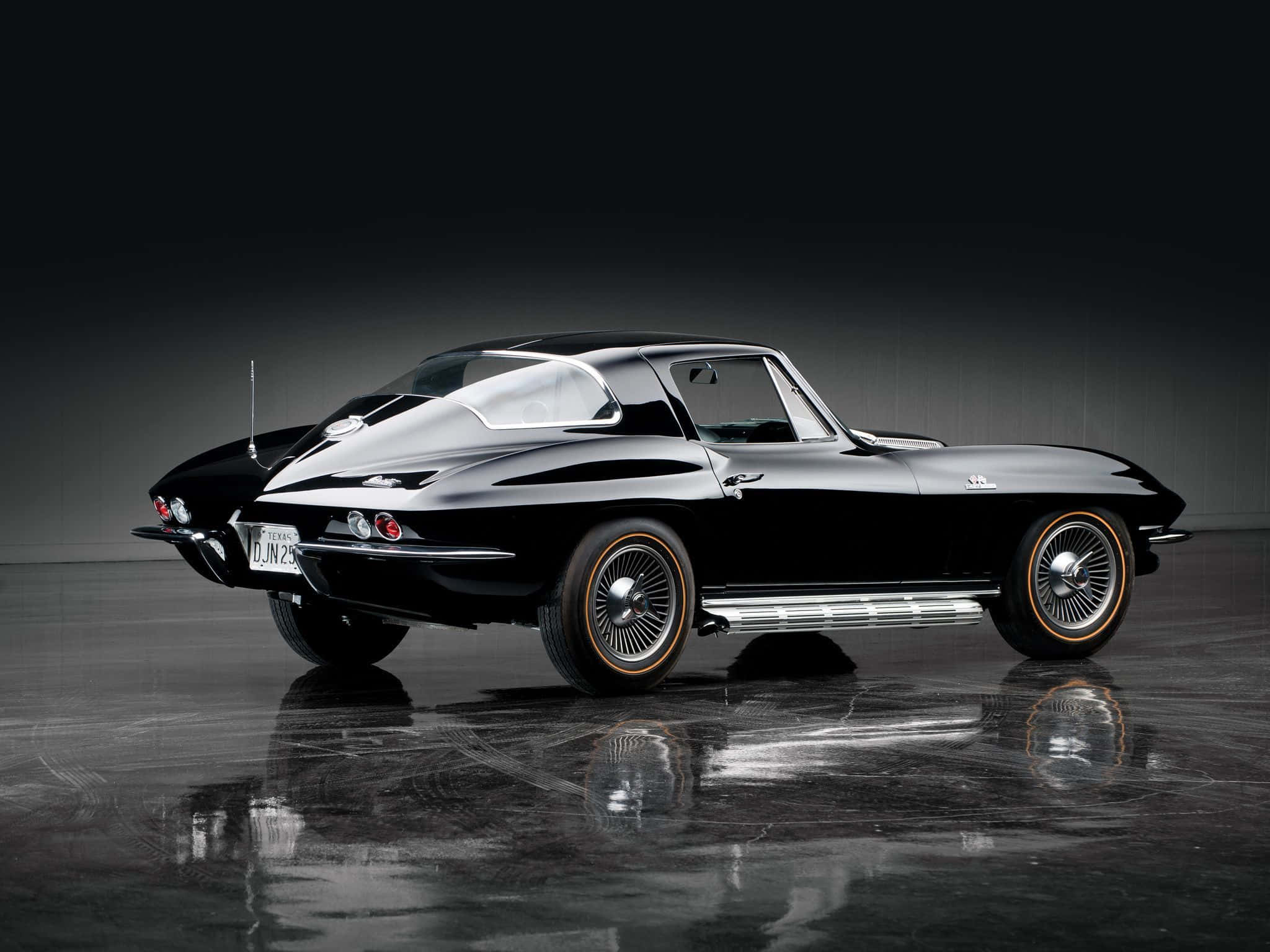 classic 桌布 壁紙 — 一架時尚的黑色經典Corvette跑車在攝影棚燈光下，於反光的深色地板上閃閃發光。
