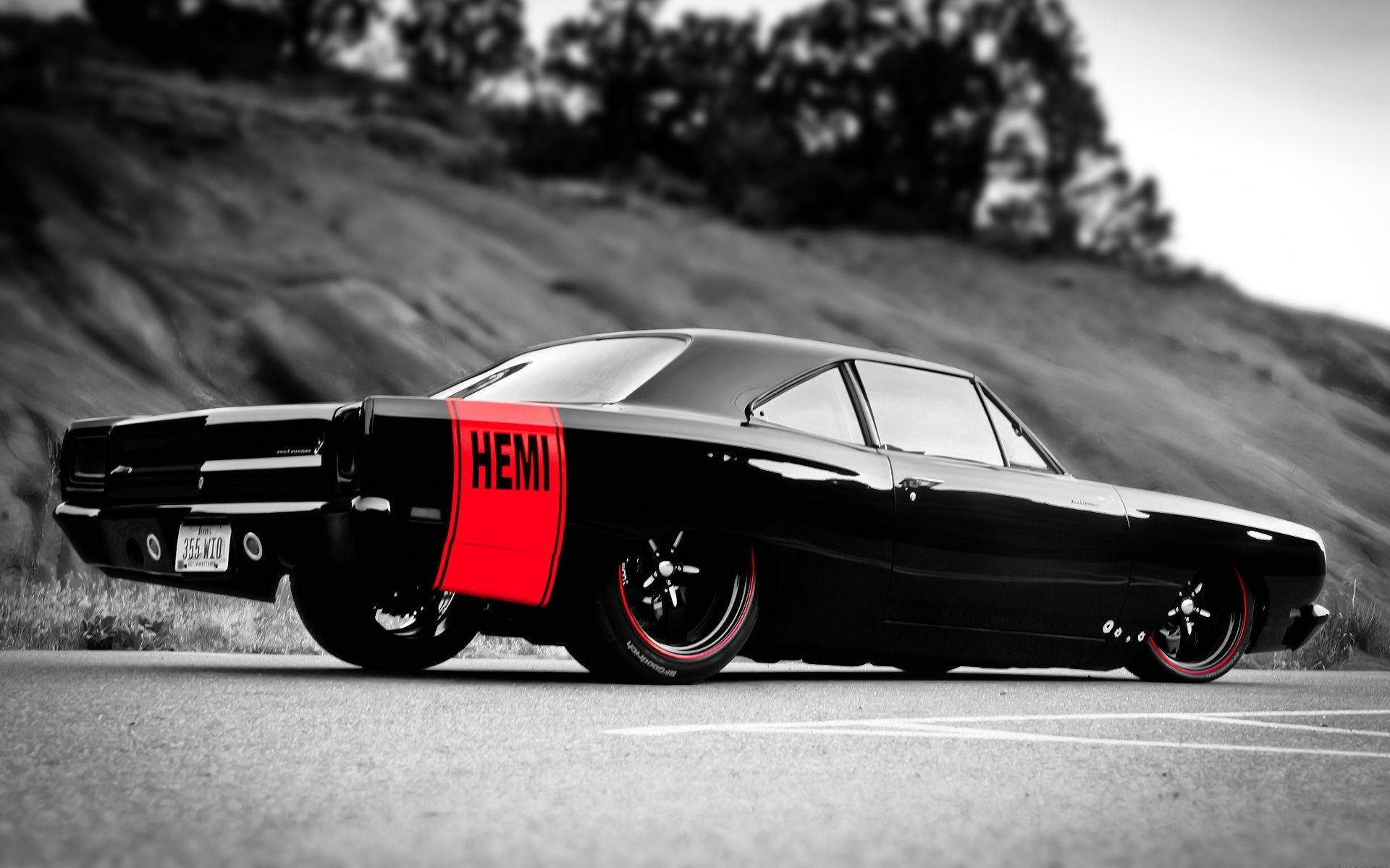 Cool Car 桌布 壁紙 — 一架時尚的黑色經典肌肉車，帶有醒目的紅色HEMI條紋，停在瀝青路上，背景是模糊的山坡。