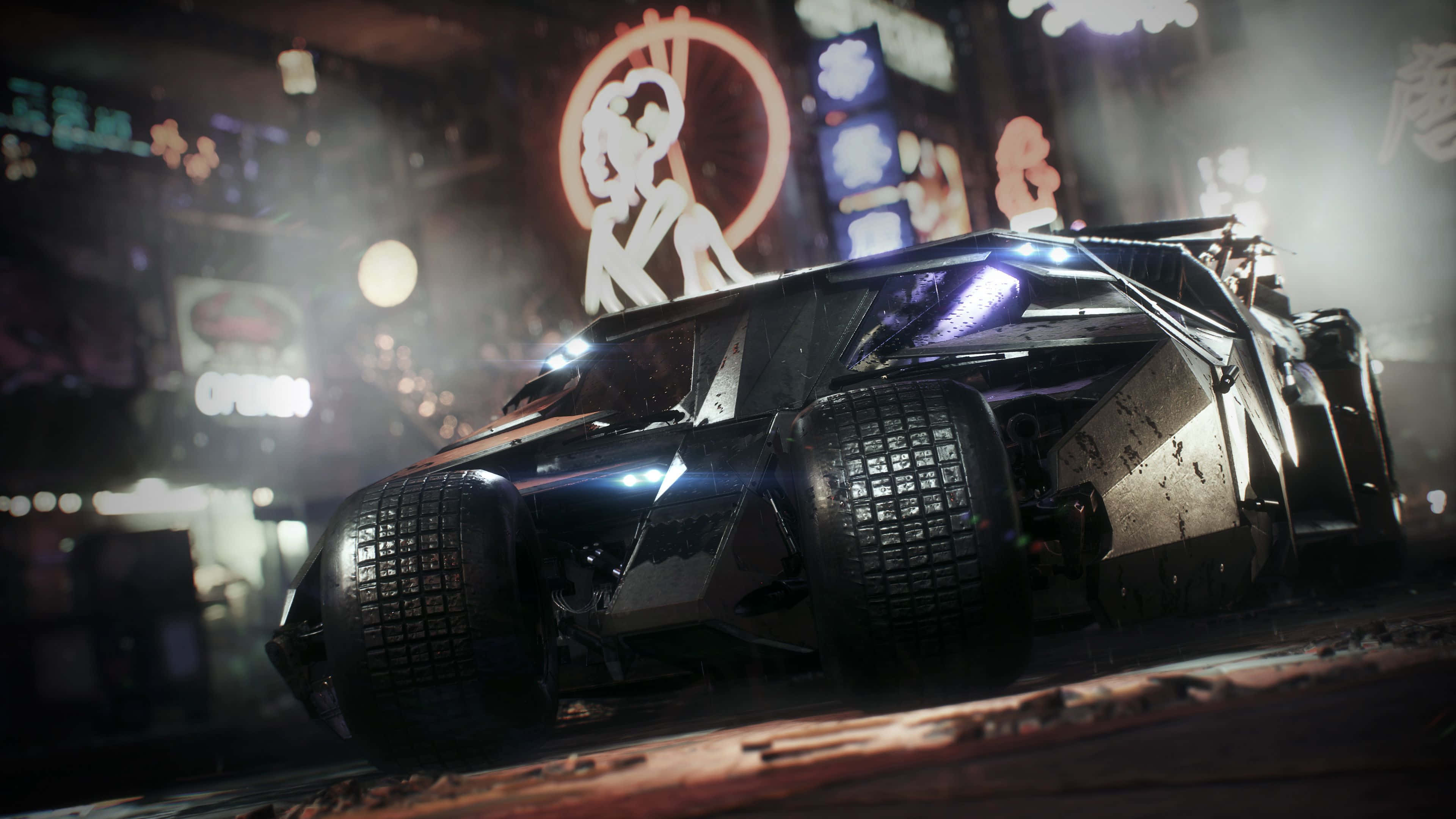 4K Batmobile 桌布 壁紙 — 一架時尚的黑色裝甲蝙蝠車在夜晚滑過霓虹燈閃爍的潮濕城市街道，伴隨著發光的招牌和濕漉漉的人行道倒影。