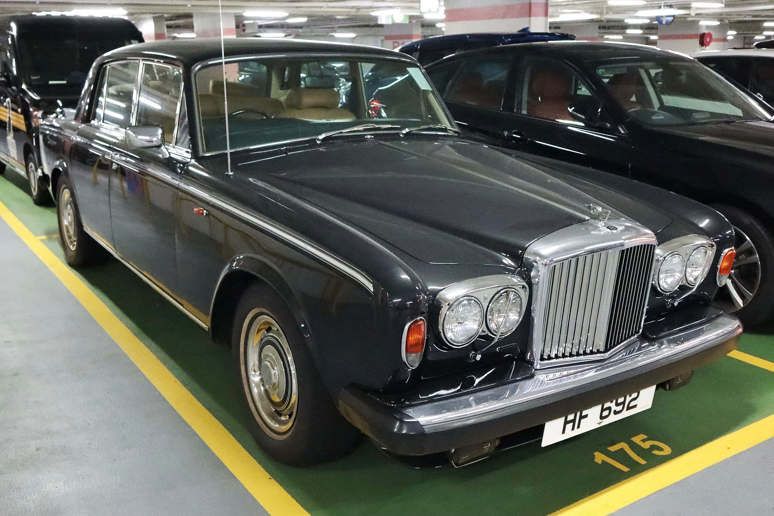 Bentley T2 桌布 壁紙 — 一架時尚的黑色賓利S1停放在光線充足、帶有黃色停車線的地下停車場。