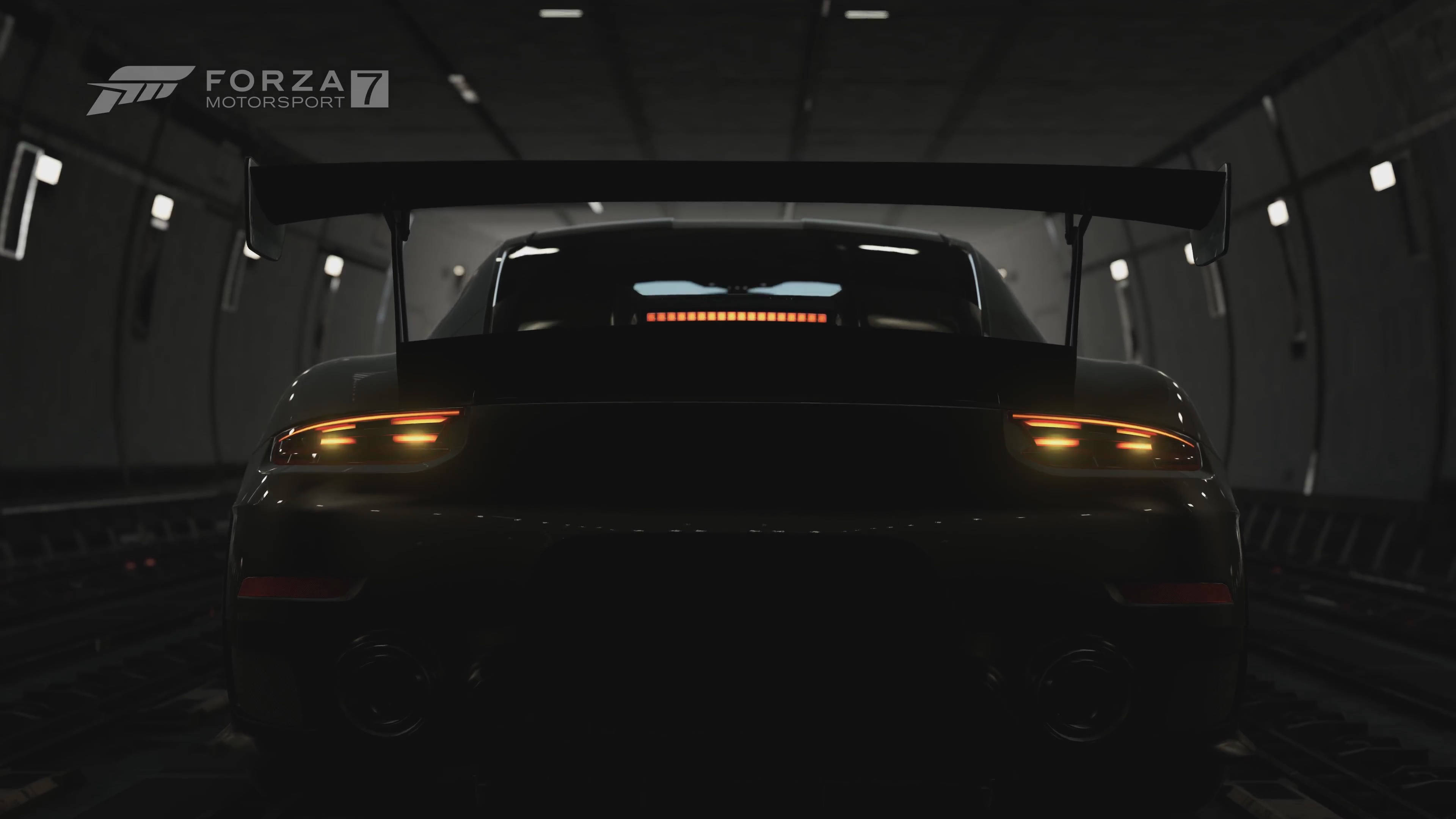 Motorsport 桌布 壁紙 — 一架時尚的黑色賽車，帶有發光的橙色尾燈，停在光線昏暗的地下隧道中。