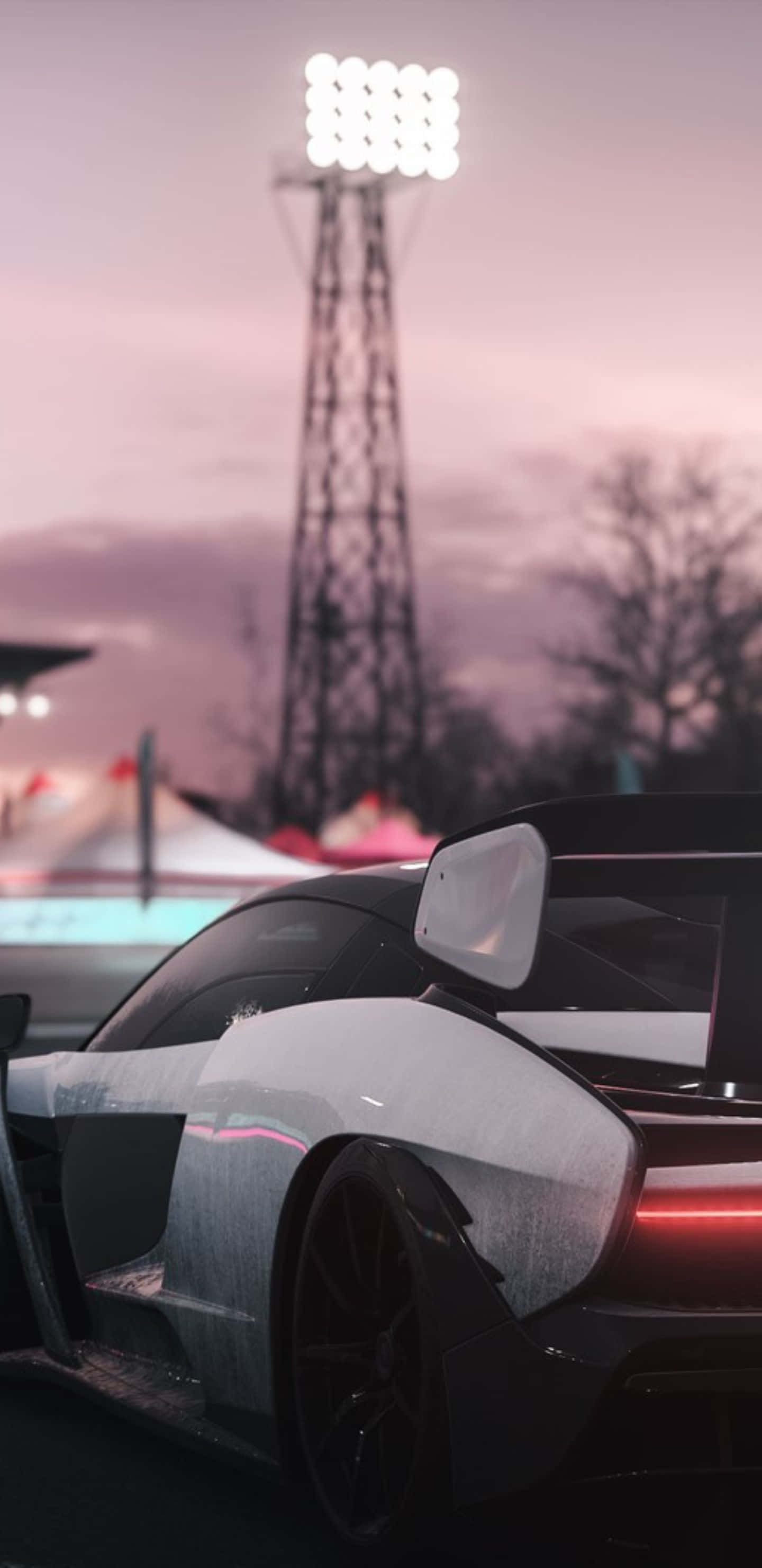Pixel 3xl Forza Horizon 4 桌布 壁紙 — 一架時尚的黑色賽車，帶有發光的紅色尾燈，停泊在暮色中的體育場燈塔下。