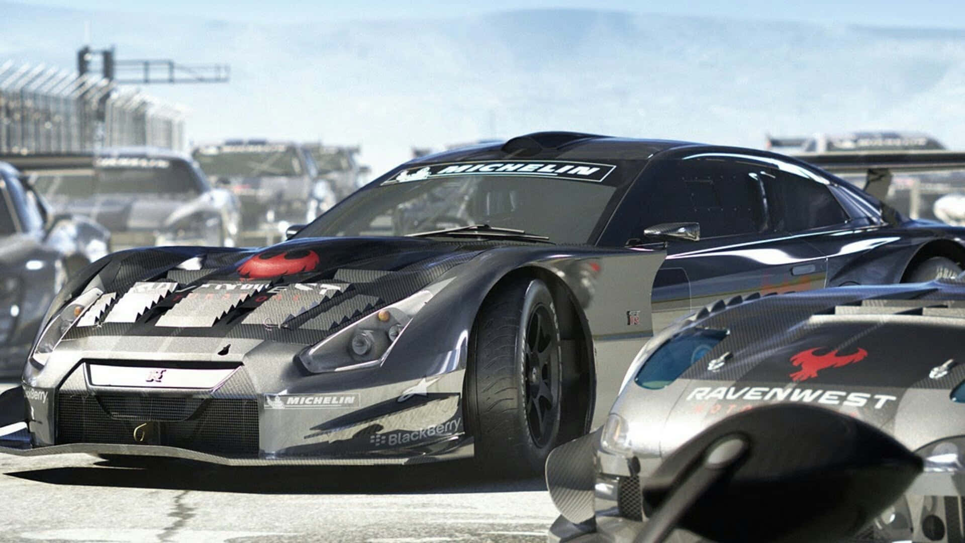 Grid Autosport 桌布 壁紙 — 一架時尚的黑色賽車，帶有碳纖維細節和米其林品牌標誌，在陽光明媚的賽道上佔據主導地位，背景有其他競爭對手。