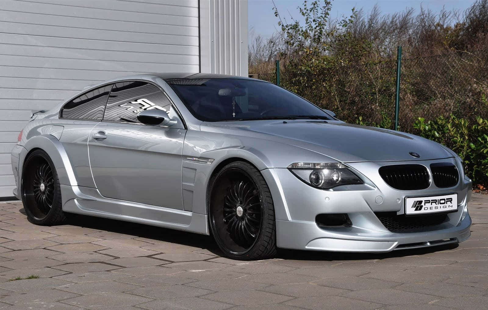 Bmw M6 桌布 壁紙 — 一架時尚銀色BMW M6雙門跑車搭配黑色輪圈，停放在白色車庫和綠植旁的鋪砌車道上。
