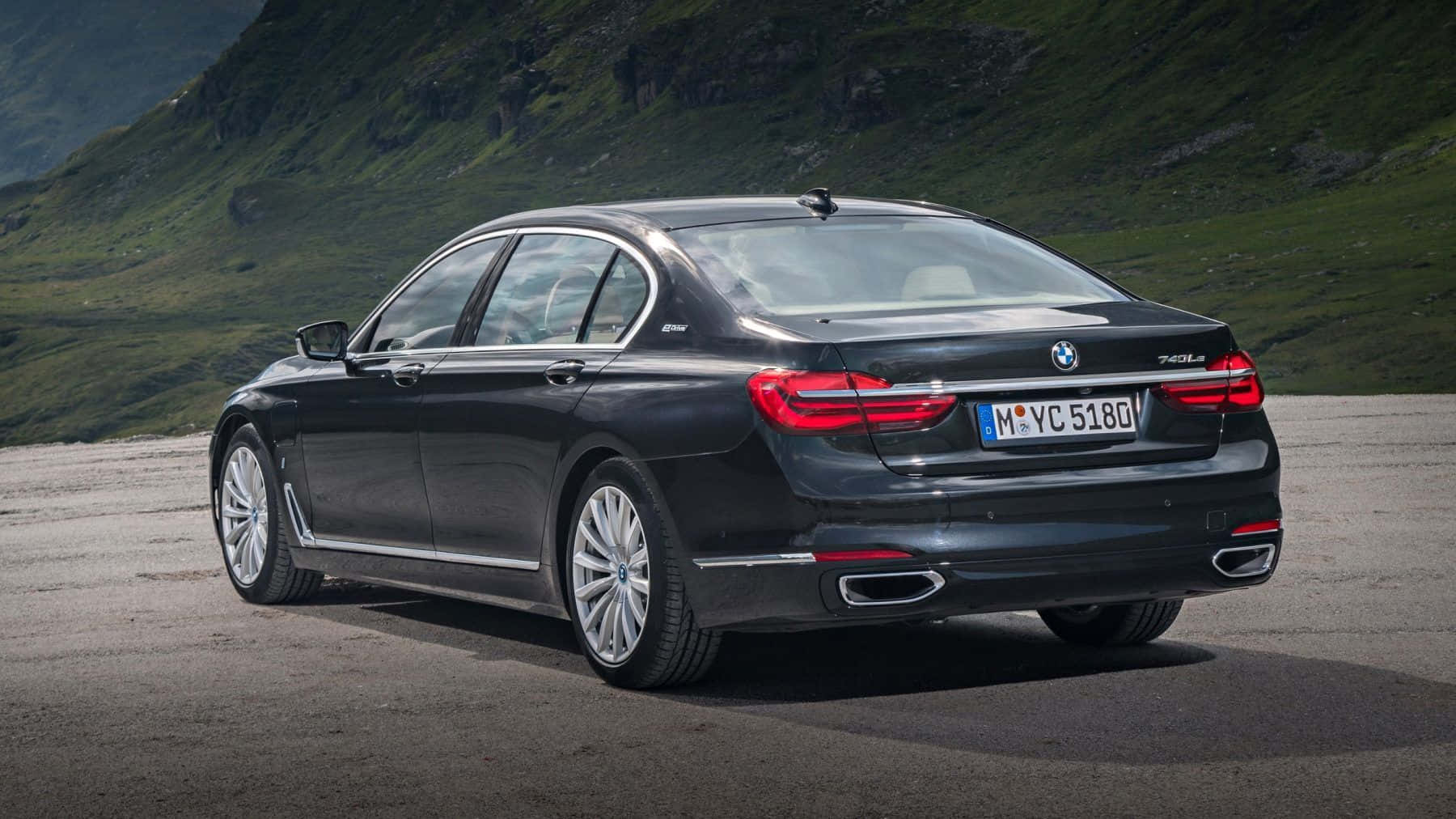 Bmw 7 Series 桌布 壁紙 — 一架時尚黑色BMW 740Li轎車停在碎石路上，背景是翠綠的山巒地帶。
