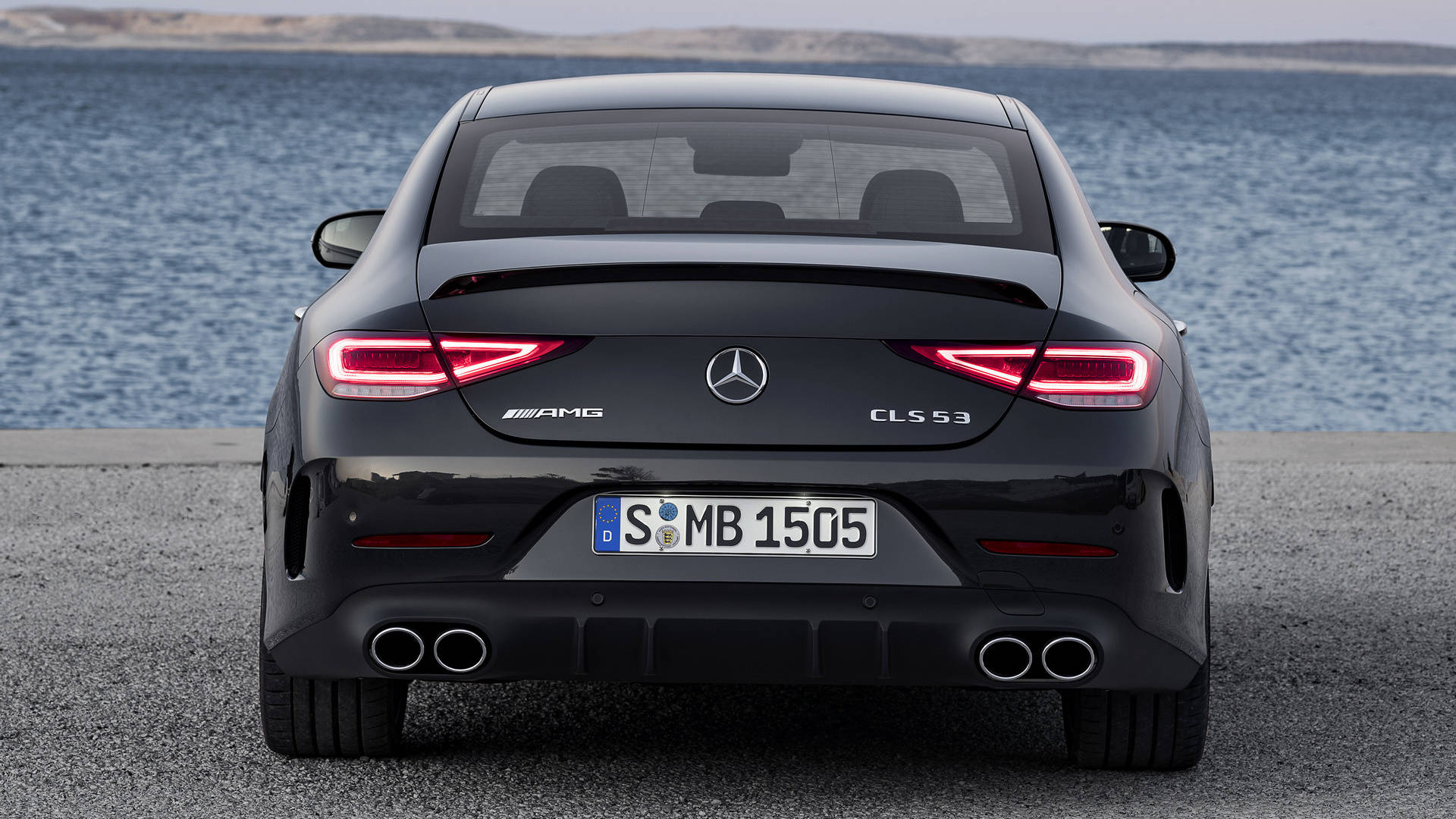 Mercedes Amg 桌布 壁紙 — 一架時尚黑色Mercedes-AMG CLS 53停在灰色路面上，背後是平靜的藍色大海。