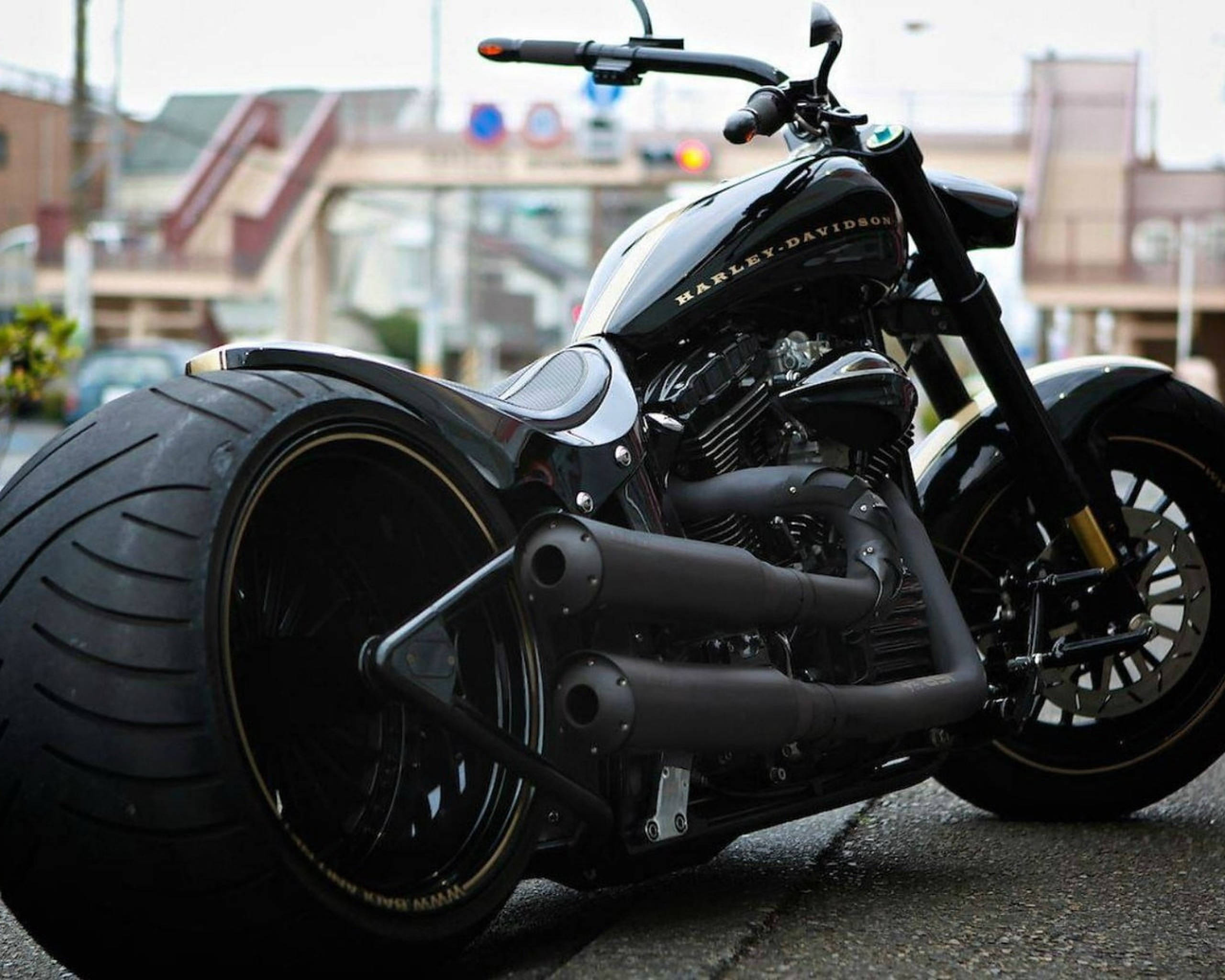 Chopper 桌布 壁紙 — 一架時尚黑色哈雷戴維森chopper機車，配備特大輪胎和鍍鉻裝飾，停放在城市街道上。