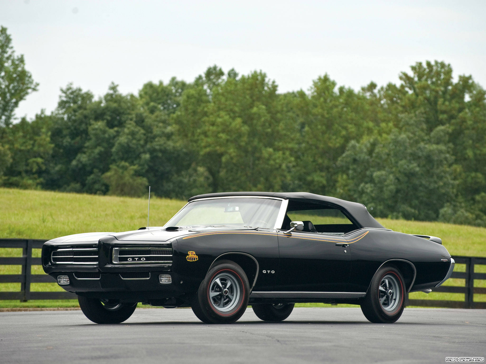 Pontiac 桌布 壁紙 — 一架時尚黑色經典Pontiac GTO敞篷車停泊在柏油路上，背景有綠樹和草地。