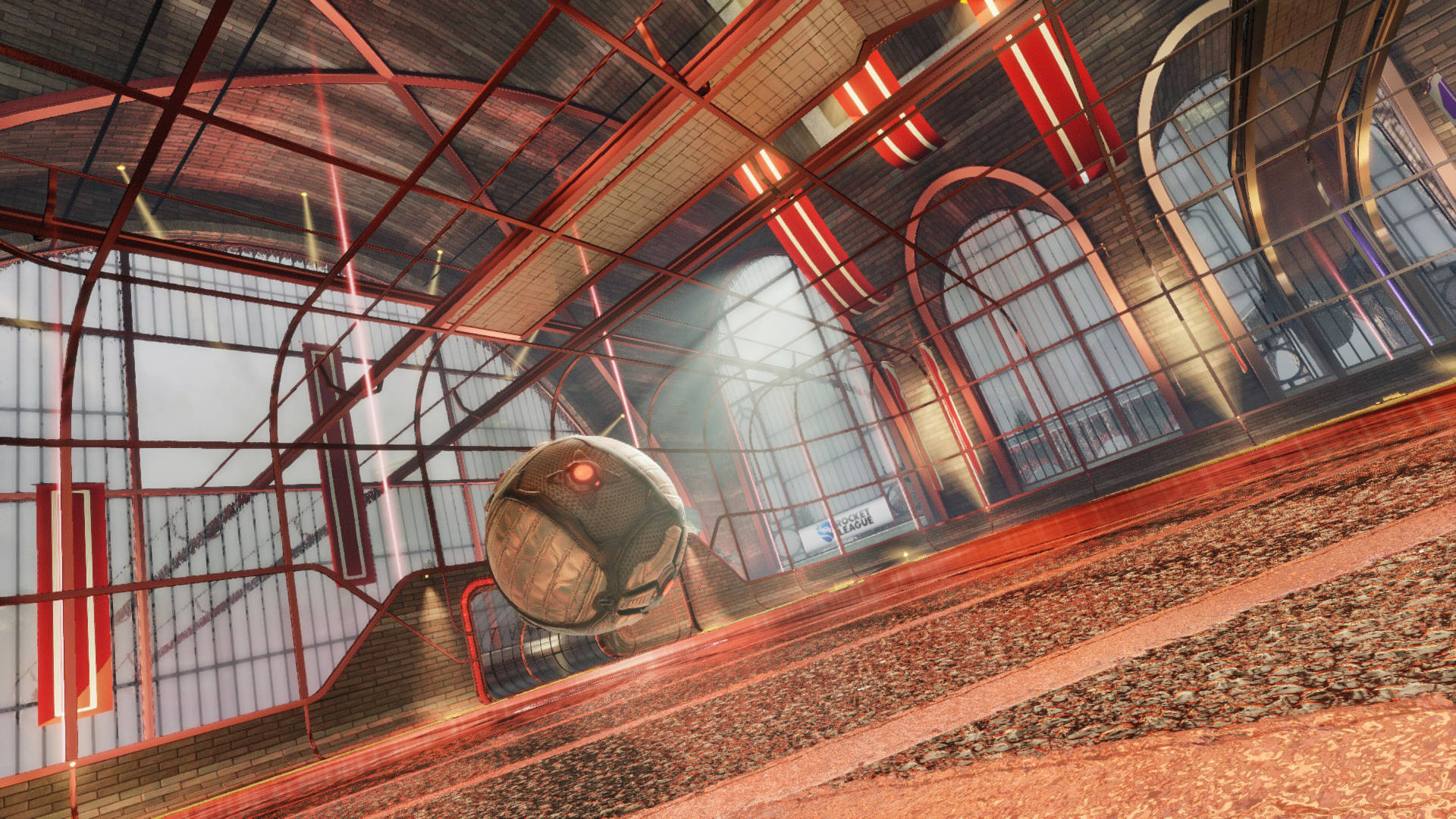 rocket league 1920x1080 桌布 壁紙 — 一架未來感十足的球形車輛停泊在一個寬敞的紅色鋼鐵和玻璃火車站內的軌道上，車站沐浴在溫暖的環境光中。