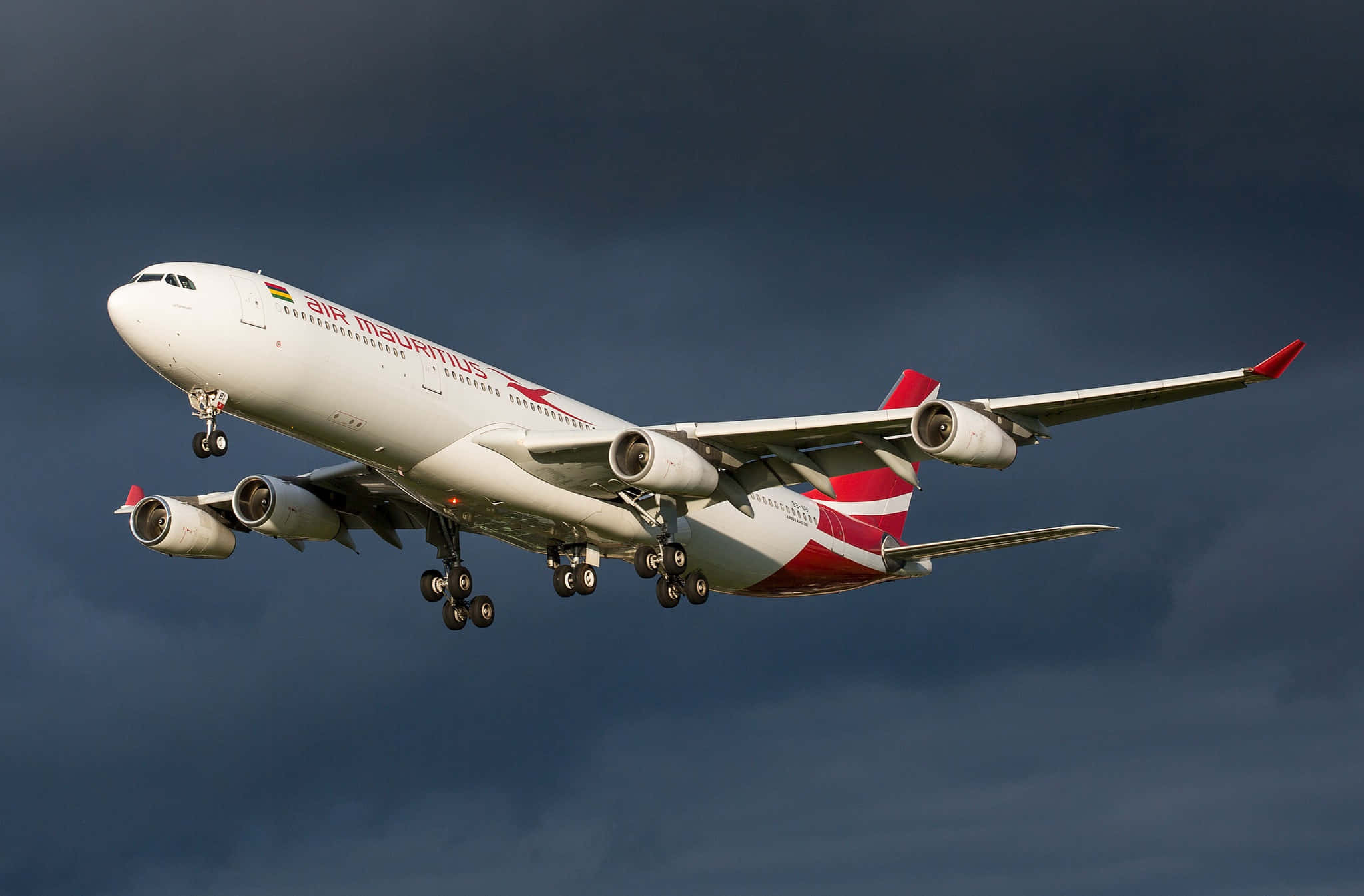 桌布 壁紙 — 一架模里西斯航空的空中巴士A340飛機在戲劇性的陰暗多雲天空下降，起落架已放下。