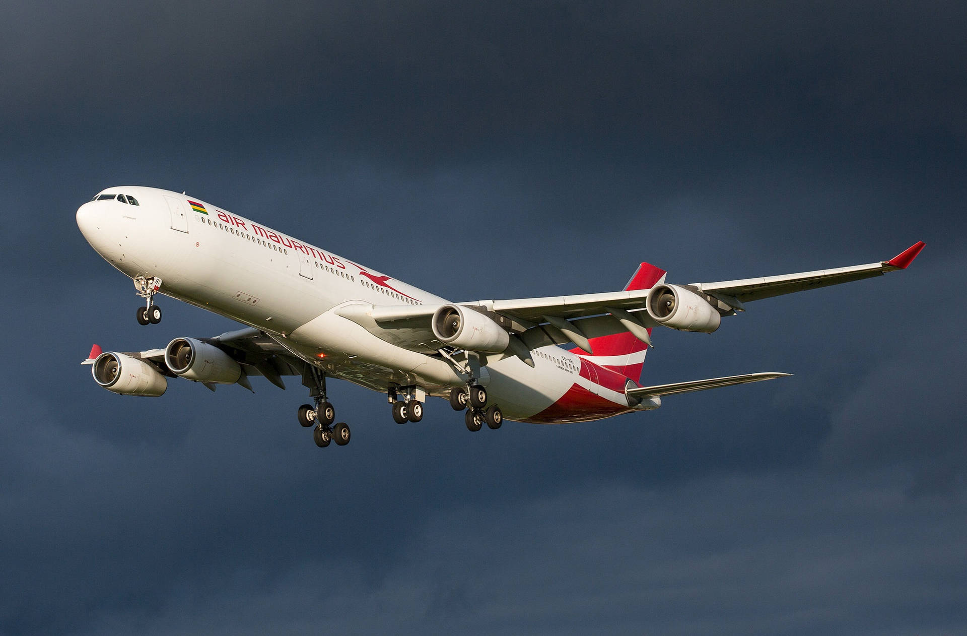 Mauritius 桌布 壁紙 — 一架模里西斯航空的空中巴士A340飛機放下起落架，在戲劇性的陰暗多雲天空中翱翔。