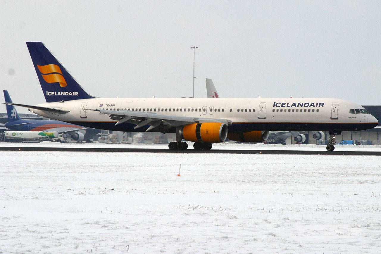 Airport 桌布 壁紙 — 一架橙色引擎的冰島航空飛機在陰天的雪地停機坪上滑行。