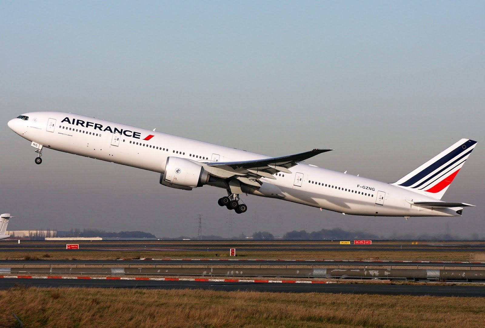 Plane 桌布 壁紙 — 一架法國航空波音777從跑道起飛，起落架伸出，背景是朦朧的天空。