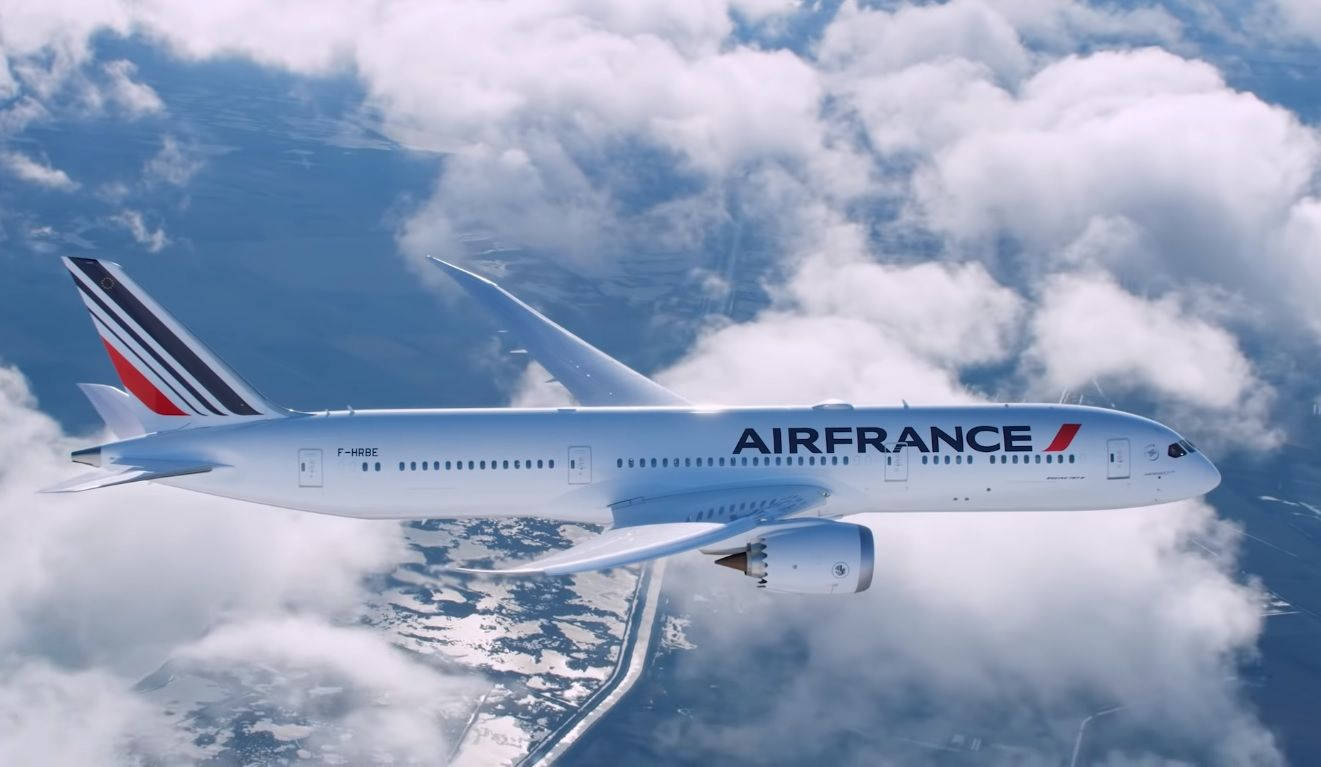 Plane 桌布 壁紙 — 一架法國航空波音787在蓬鬆的白雲上方翱翔，下方可見雪景和蜿蜒的道路。