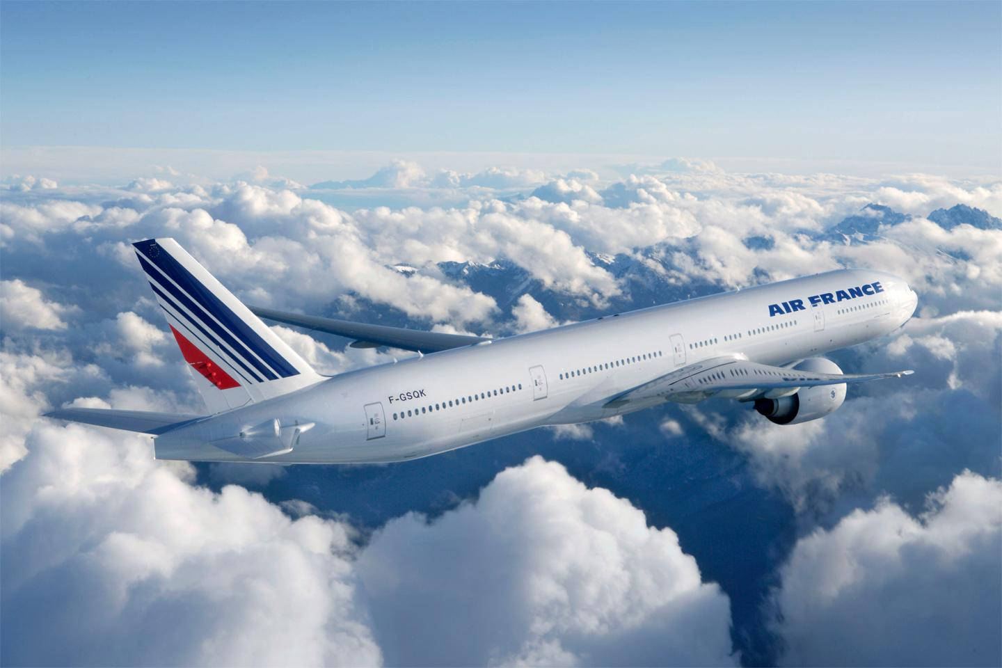 Plane 桌布 壁紙 — 一架法國航空飛機優雅地翱翔在蓬鬆的白雲之上，下方可見積雪覆蓋的山峰。