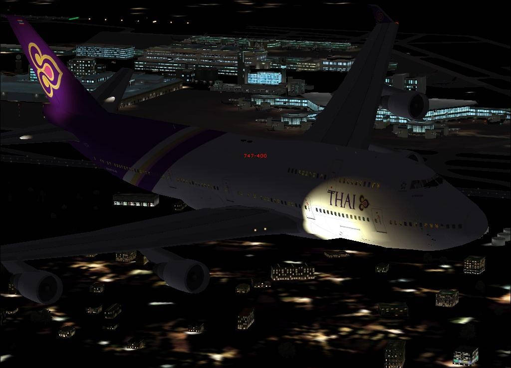Airport 桌布 壁紙 — 一架泰國航空波音747在夜間滑翔過一個廣闊而燈火通明的機場，下方城市燈光閃爍。