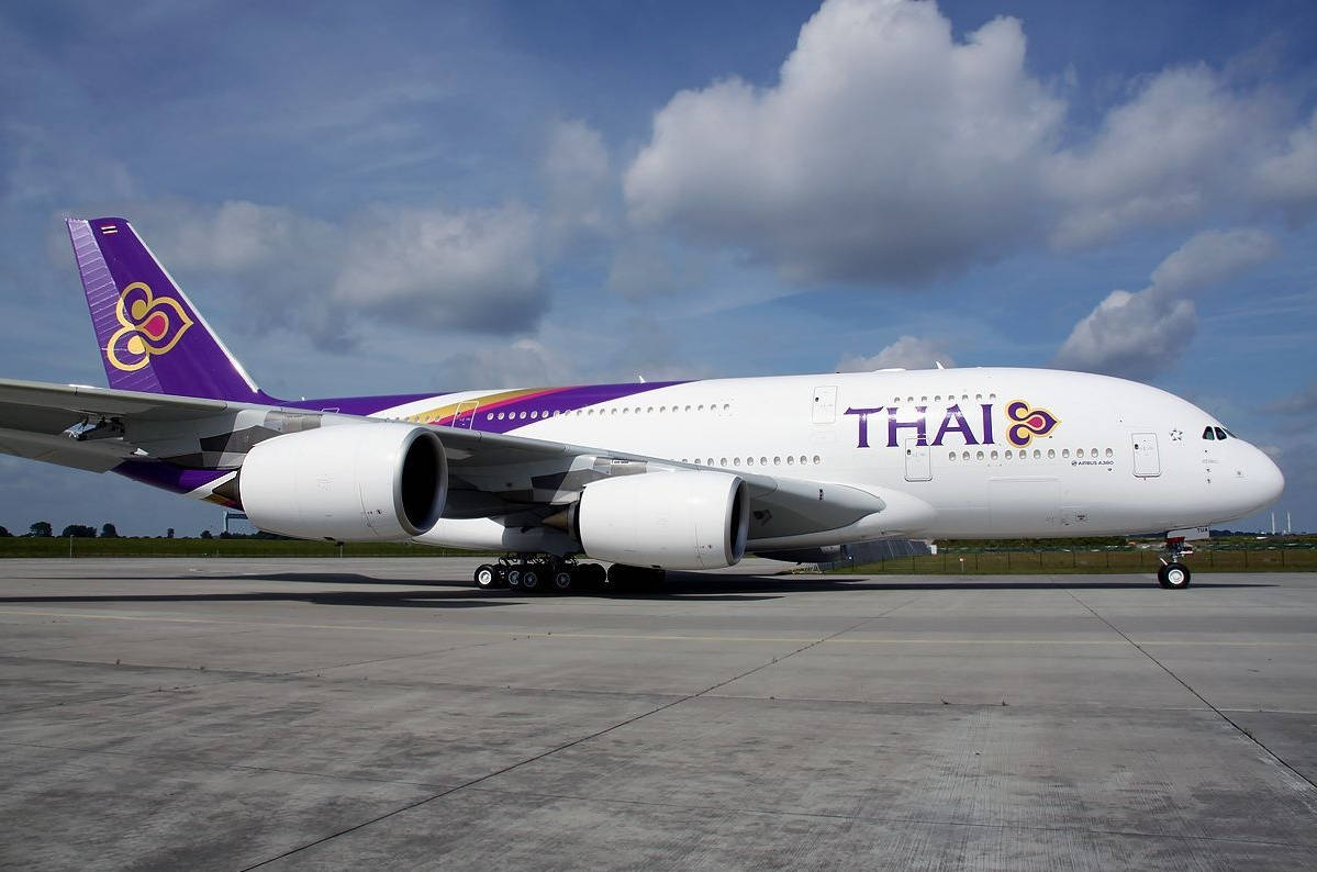 飛機 桌布 壁紙 — 一架泰國航空空中巴士A380停泊在陽光普照的停機坪上，天空多雲，藍天白雲。