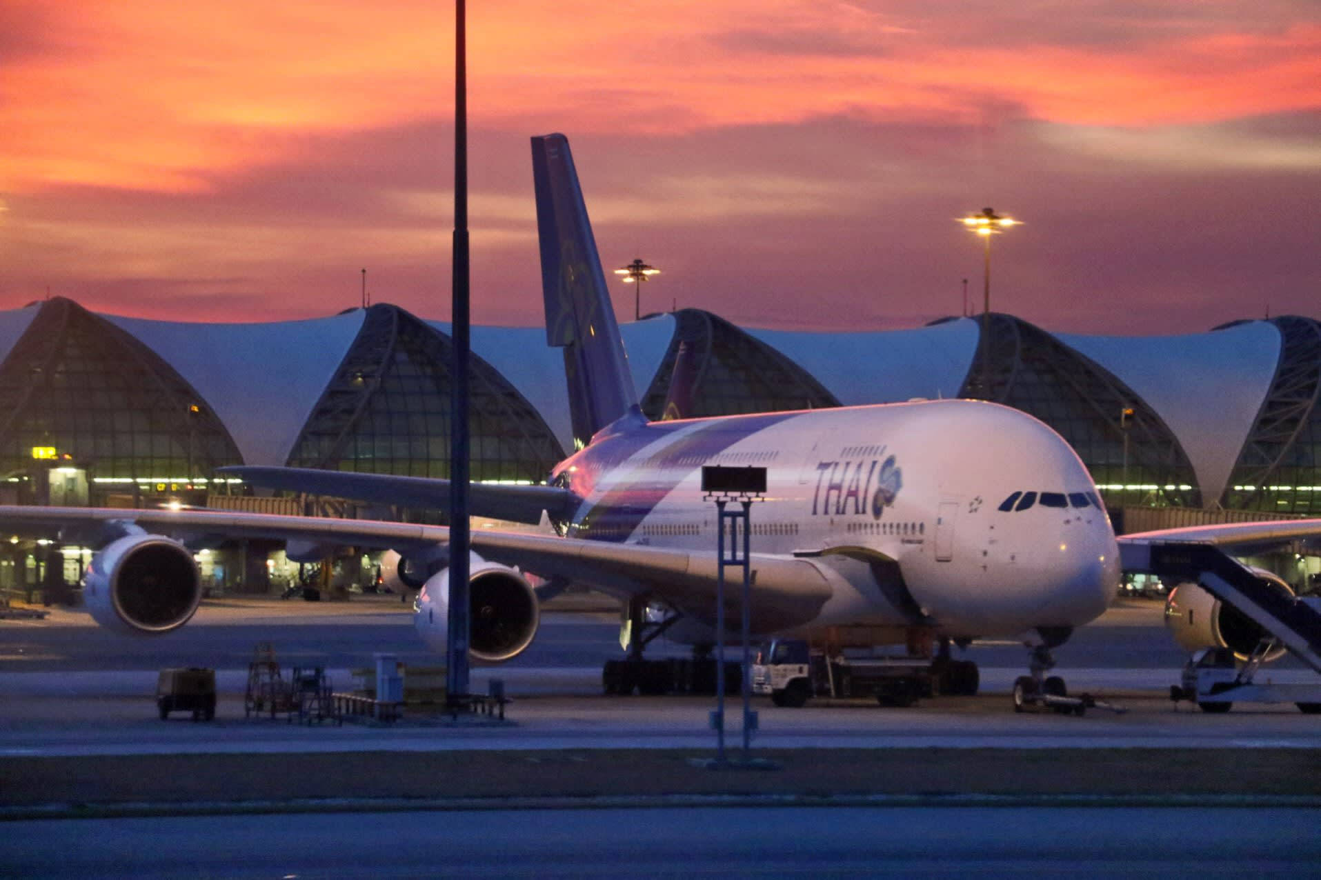 Airport 桌布 壁紙 — 一架泰國航空空中巴士A380停泊在機場停機坪上，背景是火紅的橙粉紅色日落天空。