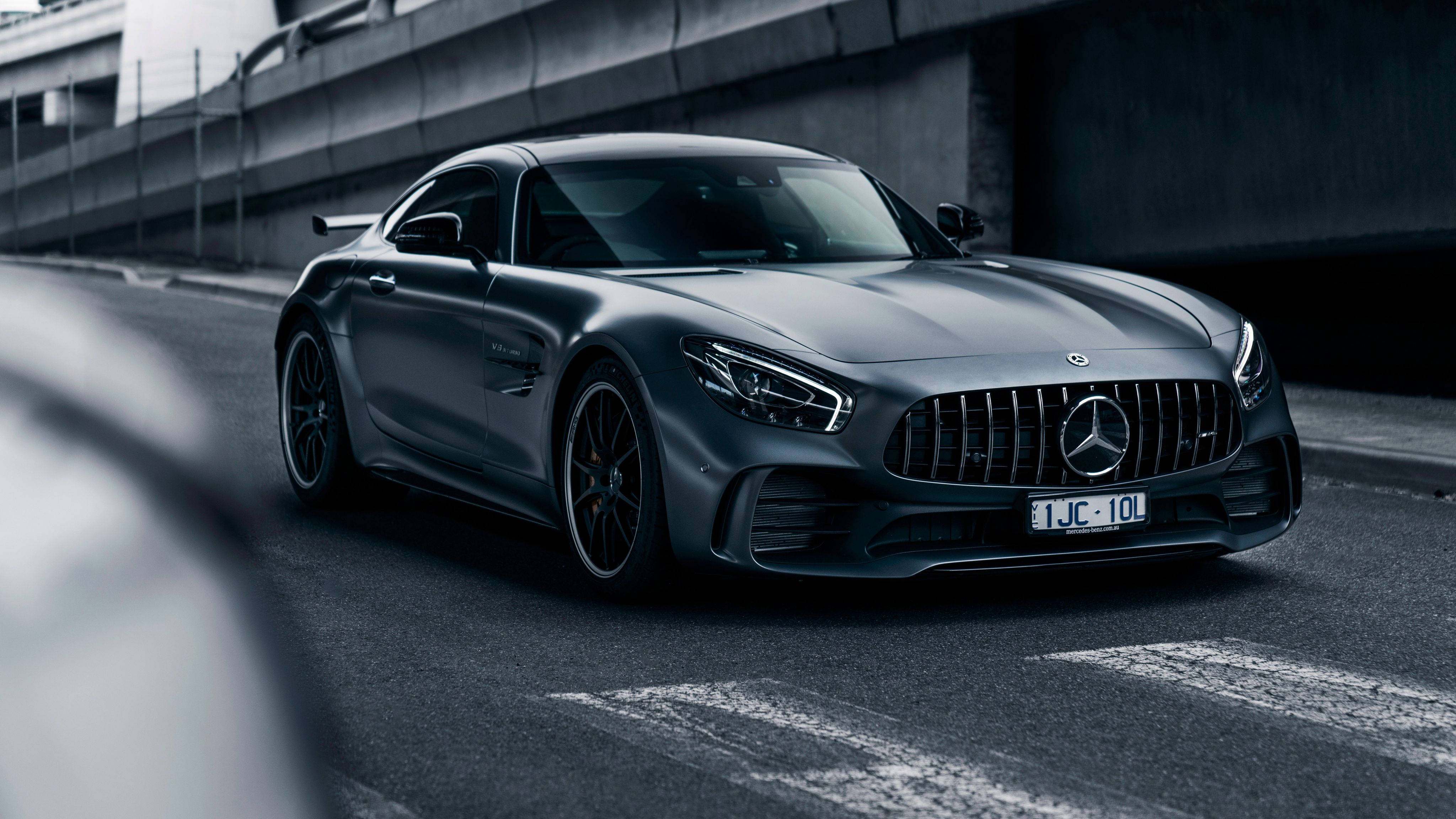 Mercedes 桌布 壁紙 — 一架流線型啞光灰色 Mercedes-AMG GT R 跑車停泊在混凝土天橋下的瀝青路上。