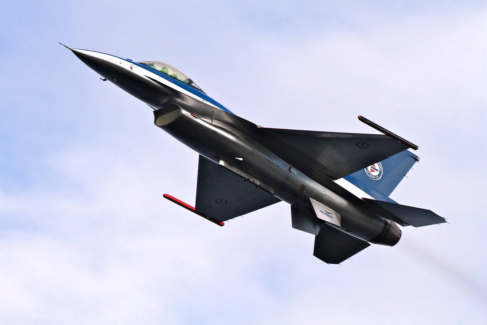 Air Force 桌布 壁紙 — 一架流線型戰鬥機在淡藍色天空和縷縷白雲中向上翱翔。