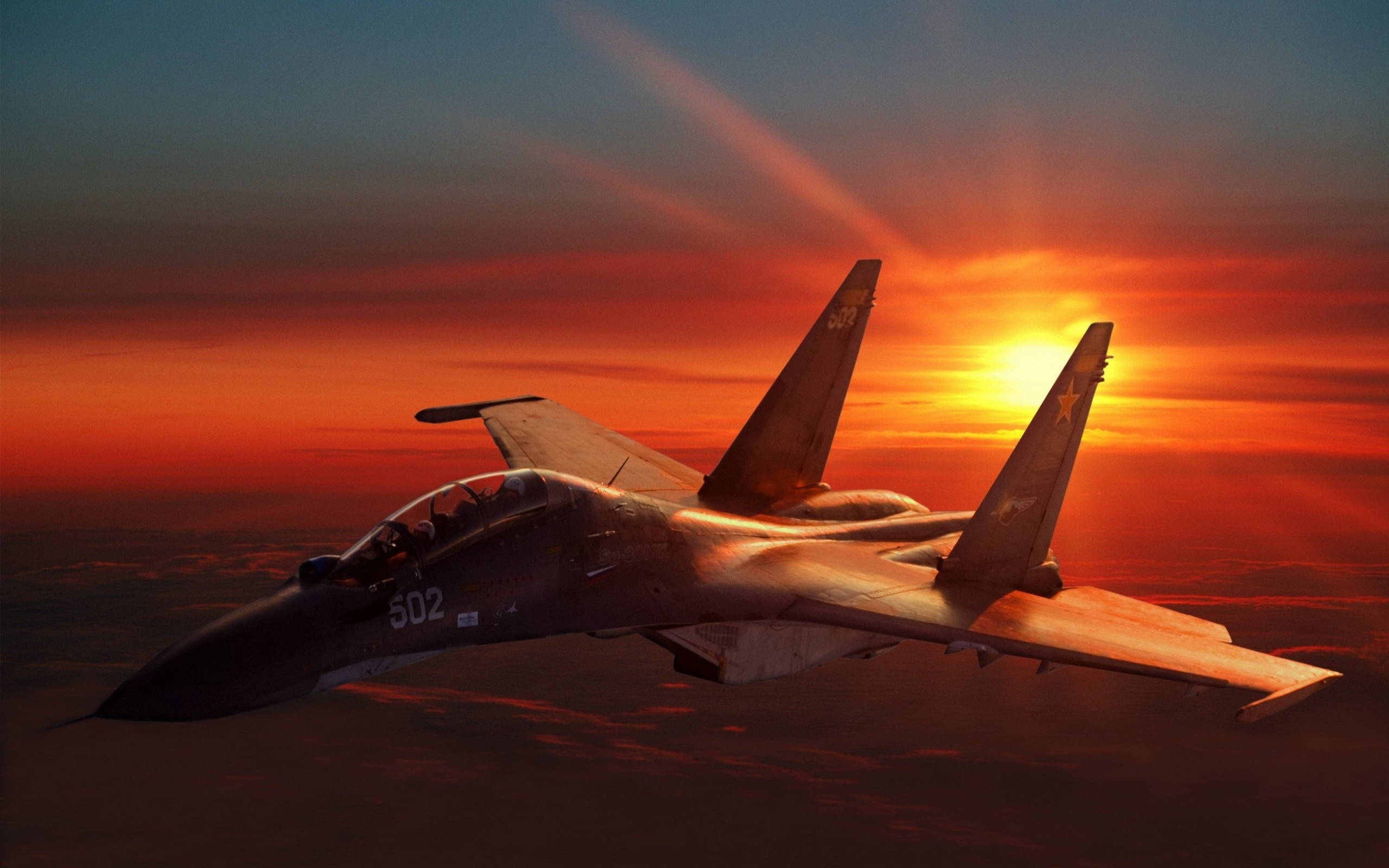 軍事動圖 桌布 壁紙 — 一架流線型戰鬥機在火紅的日落天空中翱翔，金色光線穿透下方的雲層。