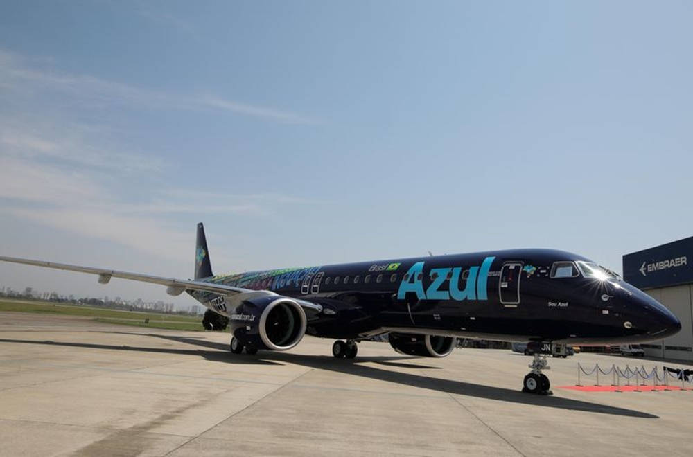飛機 桌布 壁紙 — 一架流線型深藍色Azul Airlines Embraer噴射機停在陽光普照的停機坪上，天空晴朗，遠處有跑道。
