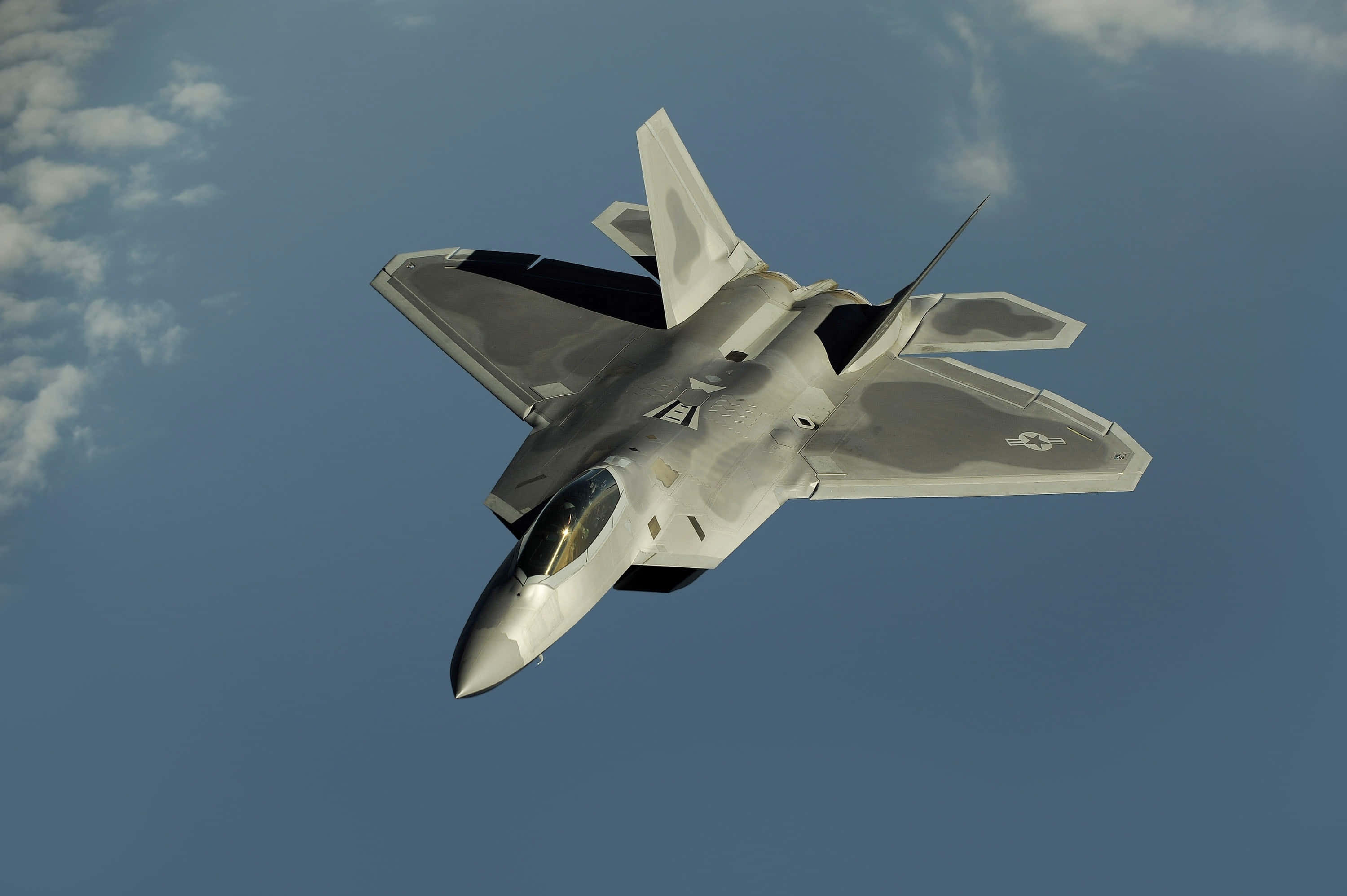 Military Plane 桌布 壁紙 — 一架流線型灰色戰鬥機在藍天白雲中翱翔。