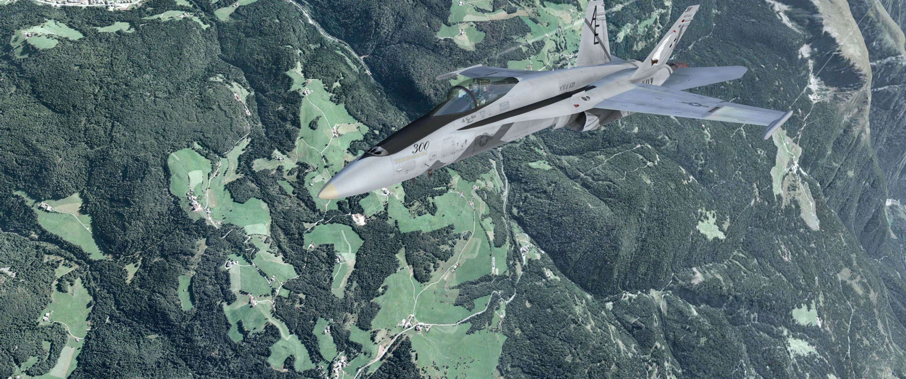 3440x1440p Microsoft Flight Simulator 桌布 壁紙 — 一架流線型灰色戰鬥機在鬱鬱蔥蔥的綠色山區地形上空翱翔，下方是蜿蜒的山谷。