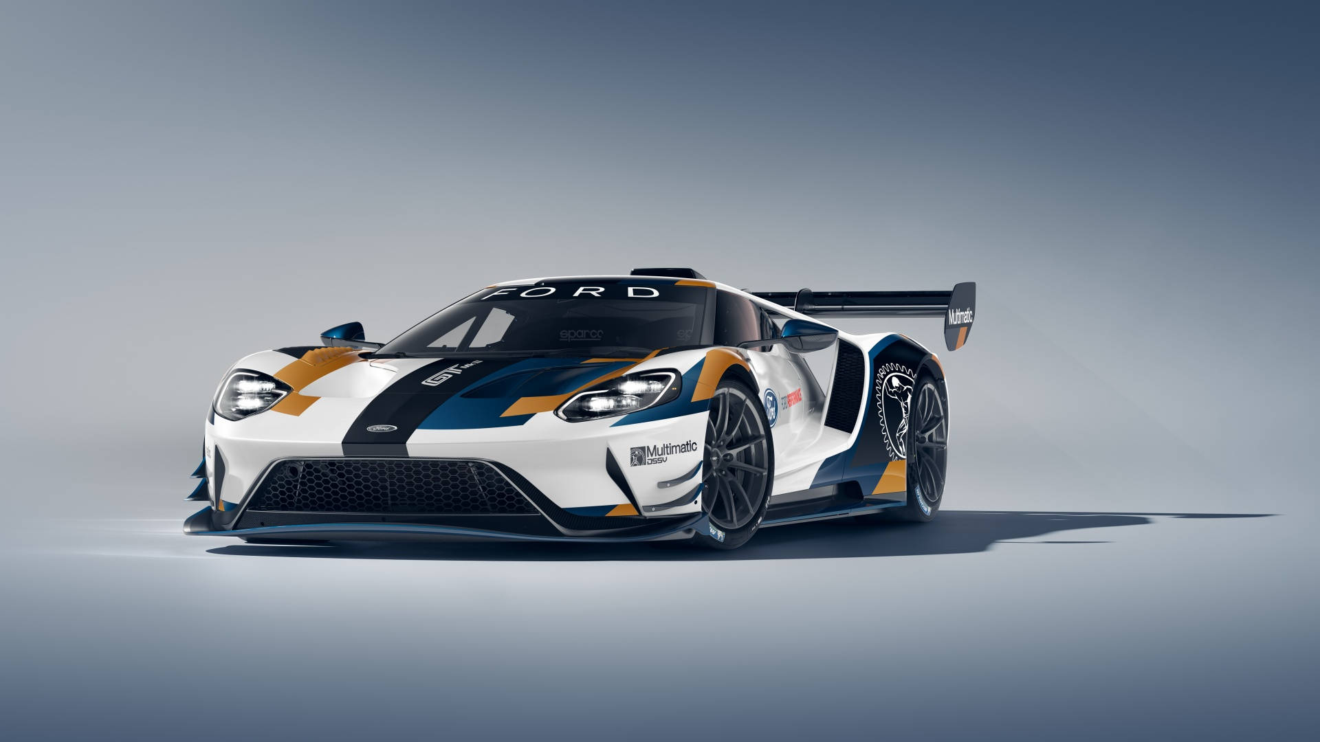 Racing 桌布 壁紙 — 一架流線型白色、藍色和金色的福特GT賽車，帶有大型後擾流板，在柔和燈光下立於簡約的攝影棚地板上。