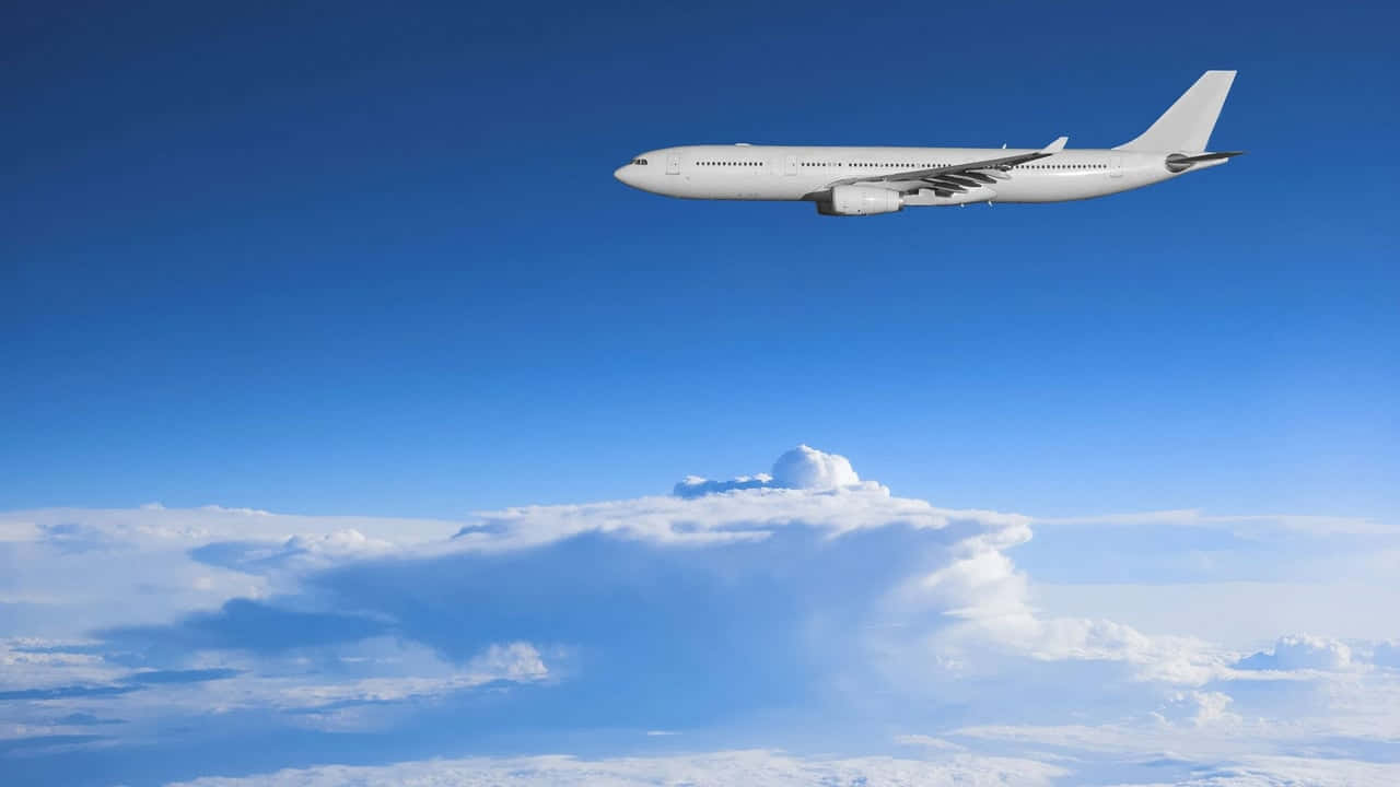 飛機 桌布 壁紙 — 一架流線型白色客機在廣闊清澈的藍天中翱翔於蓬鬆的白雲之上。