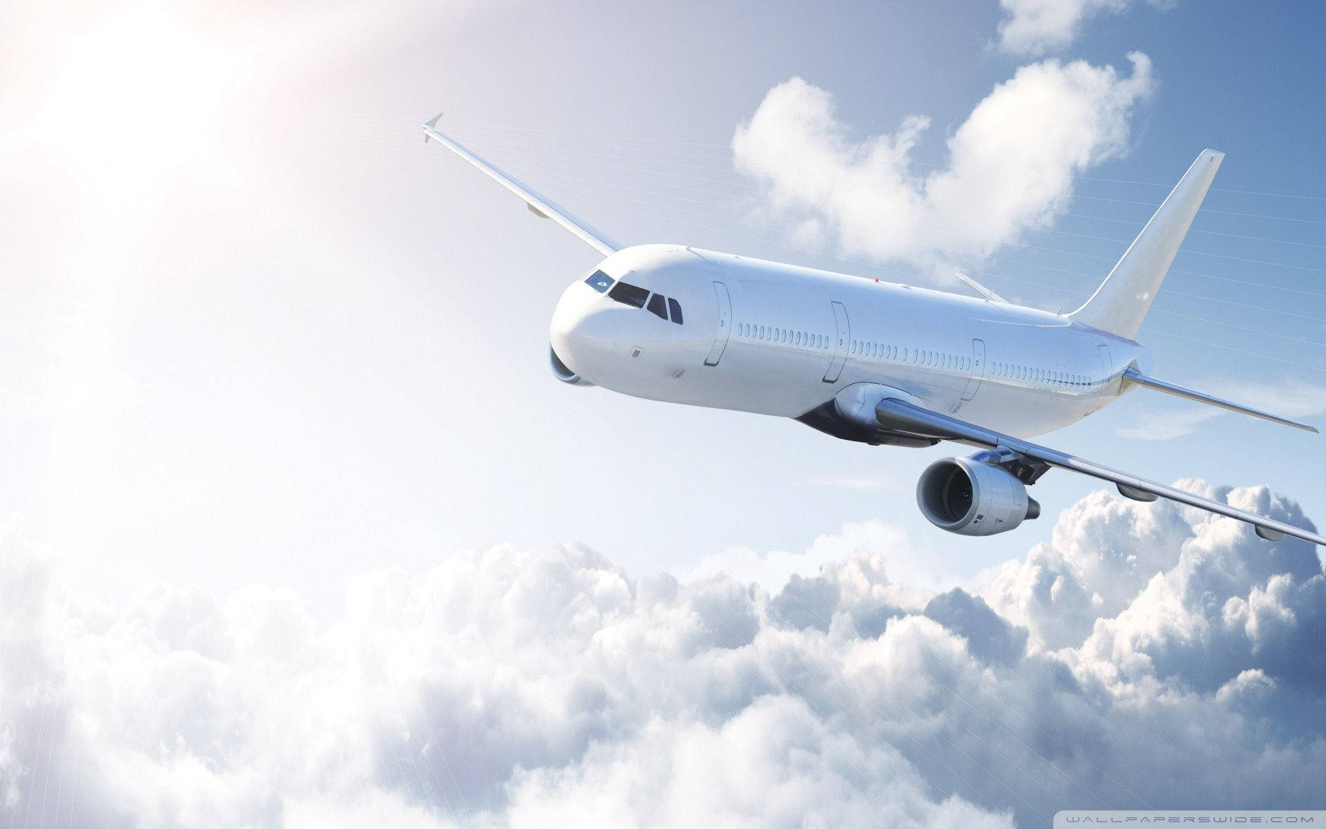 飛機 桌布 壁紙 — 一架流線型白色客機在明亮的藍天下優雅地翱翔於蓬鬆的白雲之上。