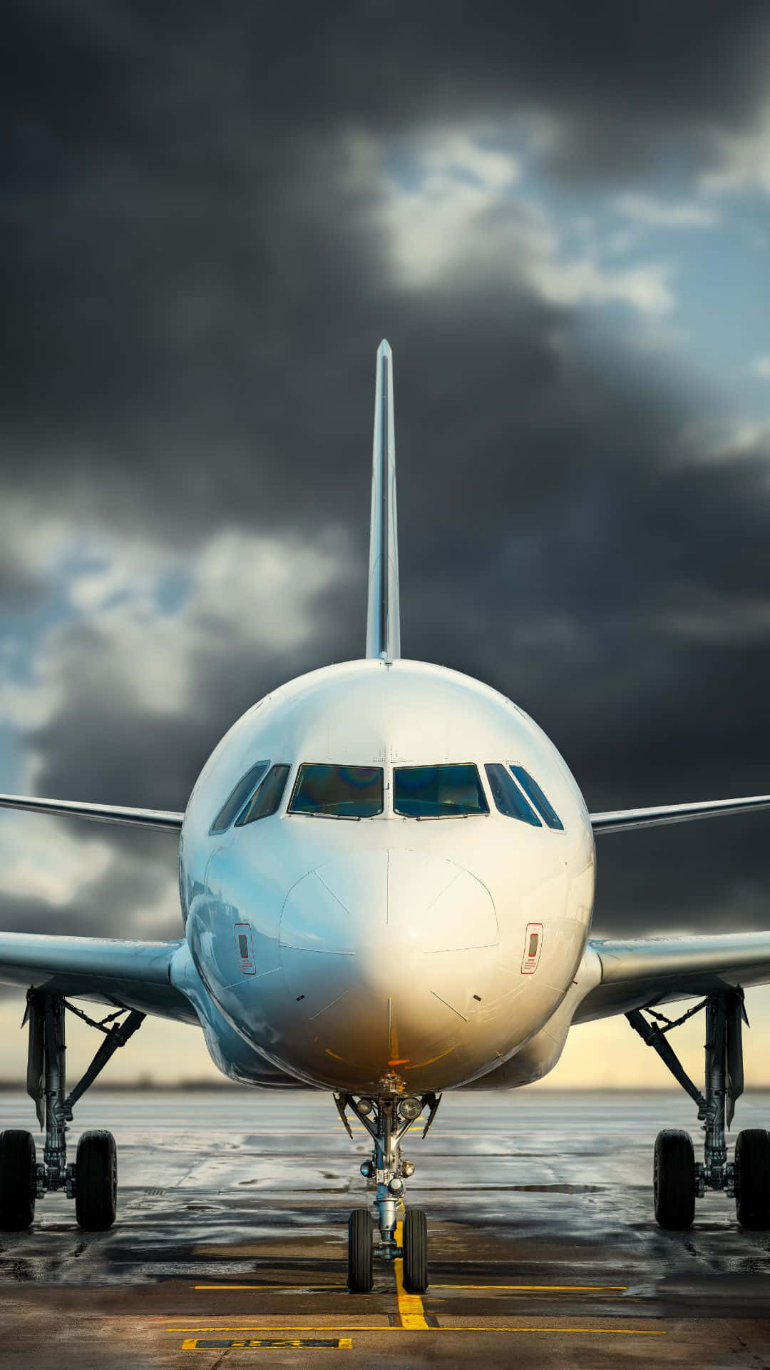 白色飛機在暴風雨天空下濕滑跑道上的正面視圖 — 飛機 壁紙