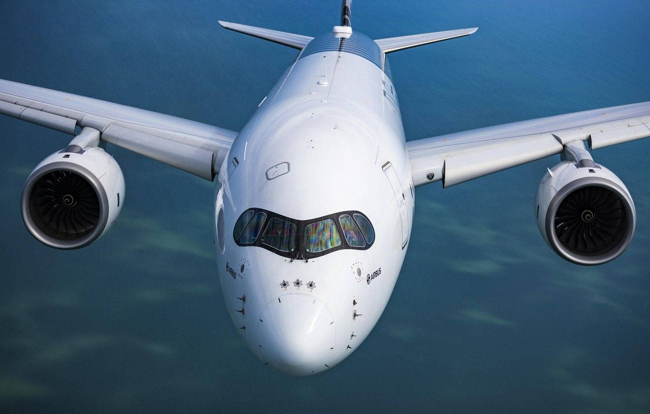 Plane 桌布 壁紙 — 一架流線型白色客機引擎轟鳴，在下方廣闊的藍色海洋上空翱翔。