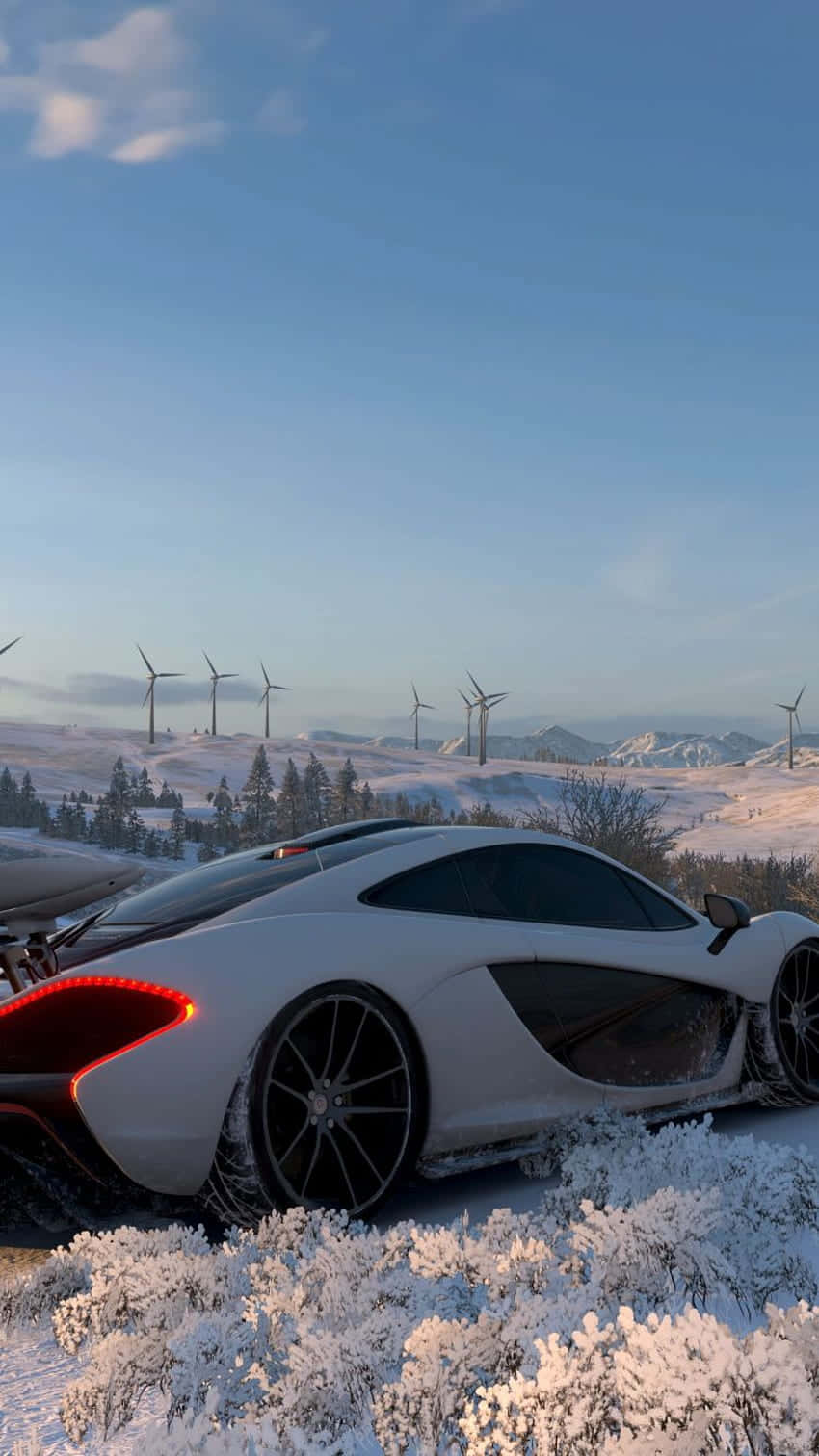 Android Forza Horizon 4 桌布 壁紙 — 一架流線型白色跑車停泊在雪地上，背景有風力發電機和積雪覆蓋的樹木，天空湛藍。