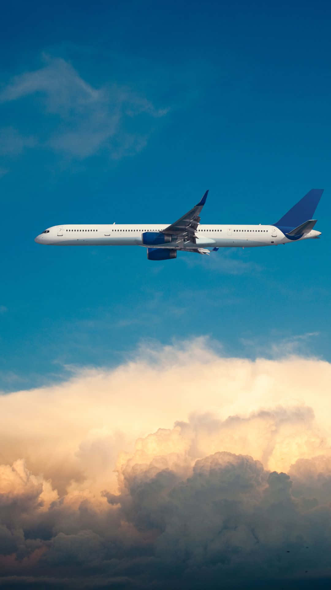 一架商用飛機在日落時分飛越色彩斑斕的雲層。 — 飛機 壁紙