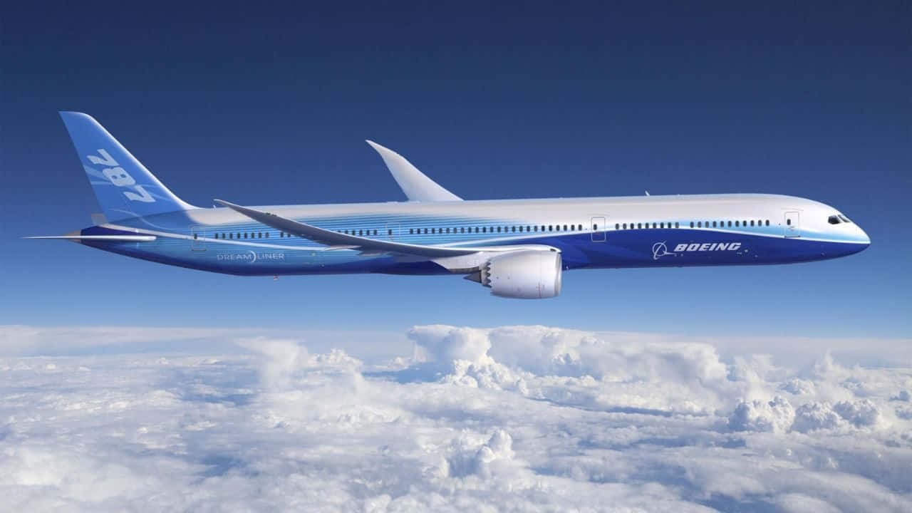 720p Plane 桌布 壁紙 — 一架流線型的藍白波音787夢想客機在晴朗的藍天下優雅地翱翔於蓬鬆的白雲之上。