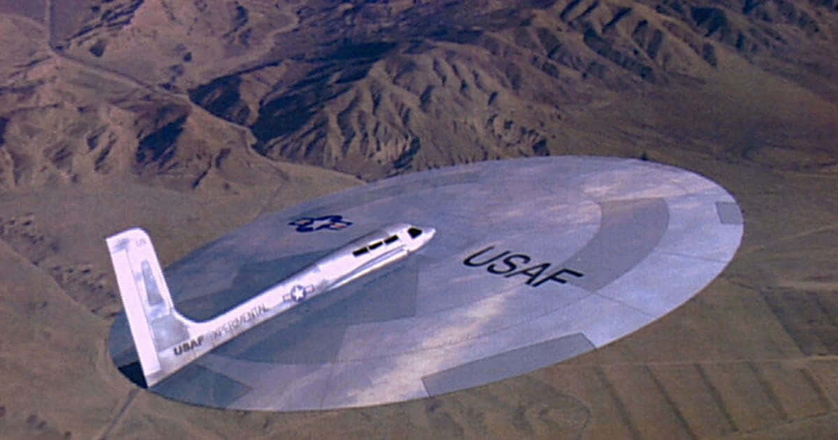 沙漠 桌布 壁紙 — 一架流線型的銀色美國空軍飛機在晴朗的天空中翱翔於崎嶇的棕色山脈之上。