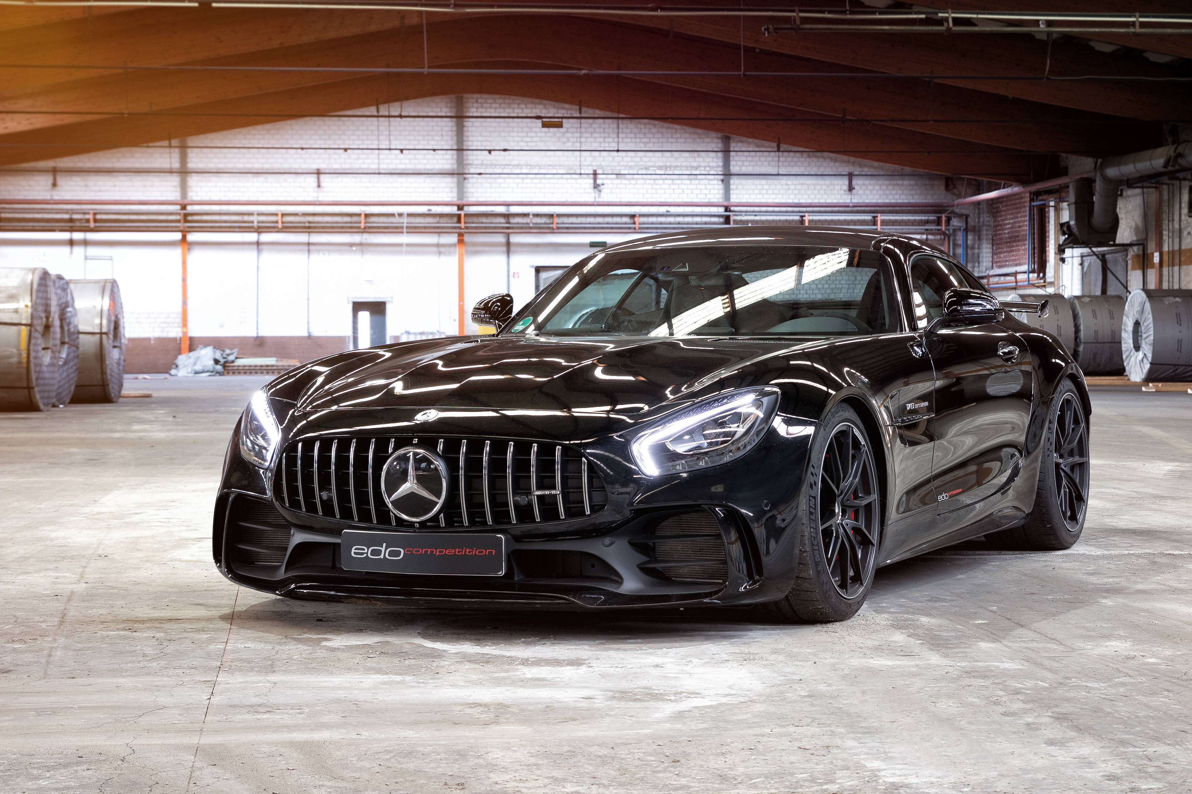 Gtr 桌布 壁紙 — 一架流線型的黑色 Mercedes-AMG GT R 跑車在寬敞倉庫的工業照明下閃閃發光。