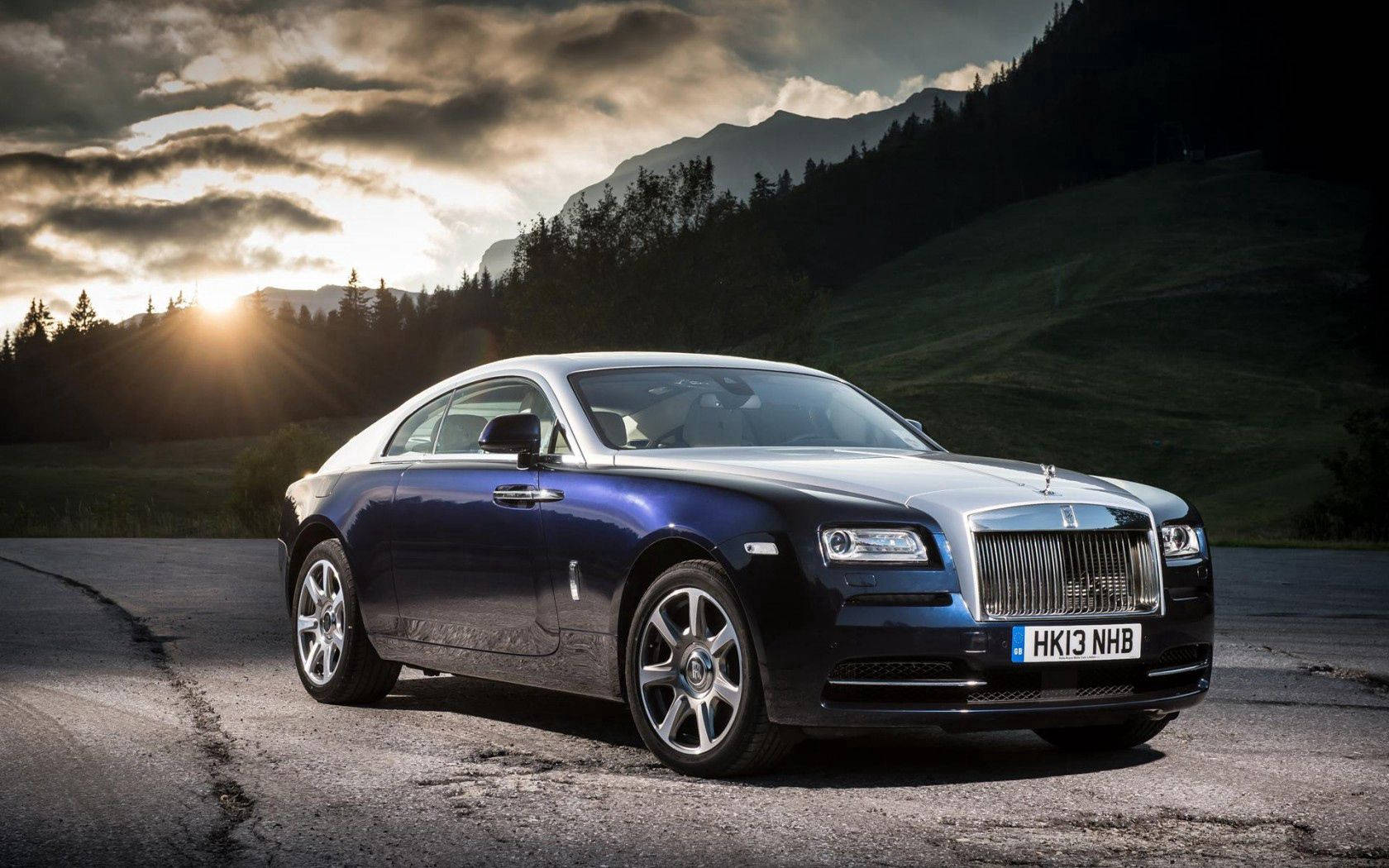 Royce 桌布 壁紙 — 一架流線型藍色 Rolls Royce Wraith 在金色夕陽下，以山巒為背景閃閃發光。