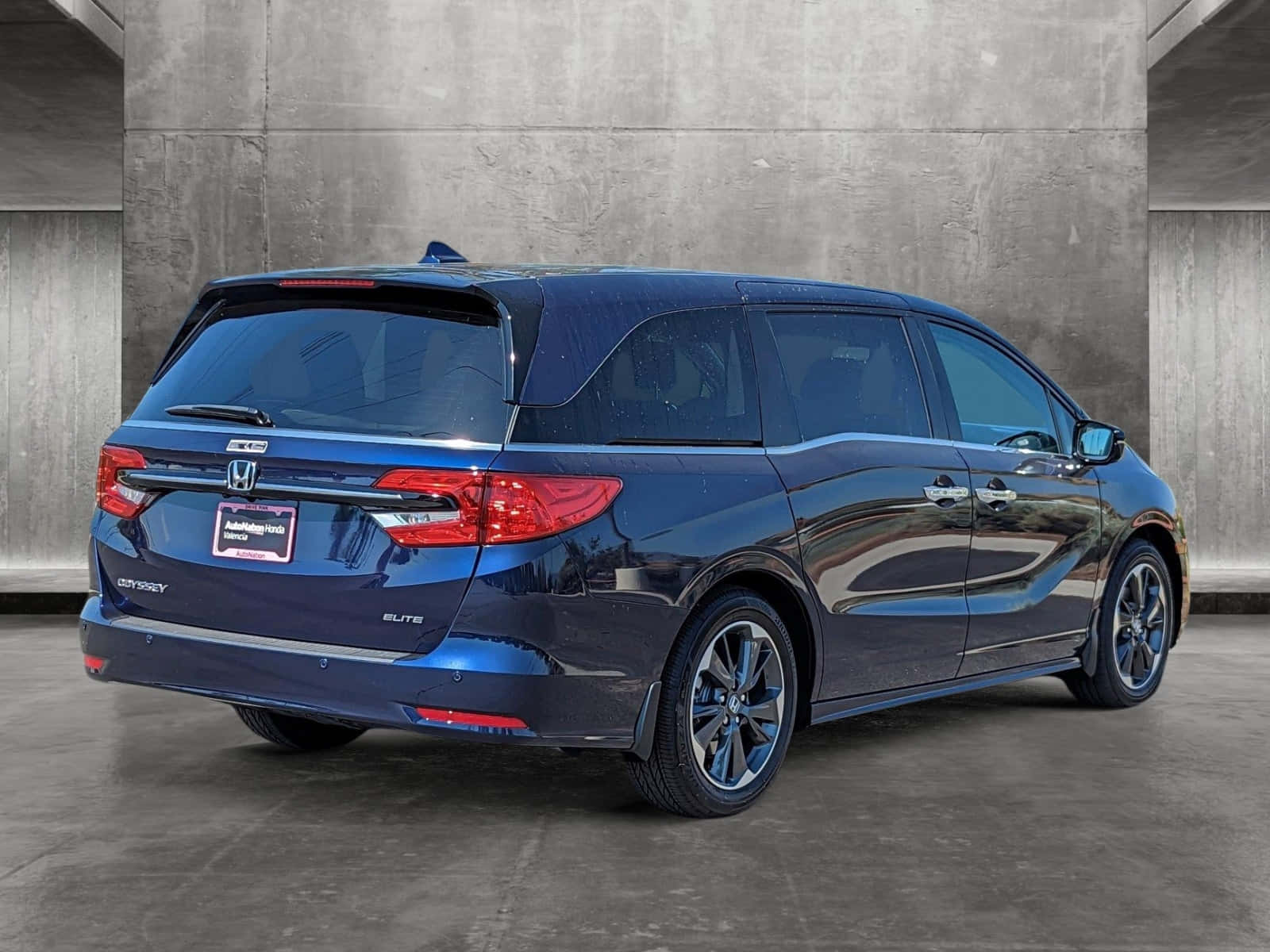 Honda Odyssey 桌布 壁紙 — 一架流線型藍色本田 Odyssey Elite 小型貨車停放在帶有反射表面的紋理混凝土牆旁。