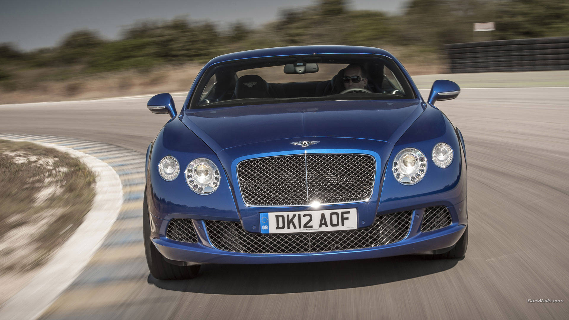bentley HD 桌布 壁紙 — 一架流線型藍色賓利 Continental GT 在賽道上疾馳，動態模糊效果突顯其動力與奢華。