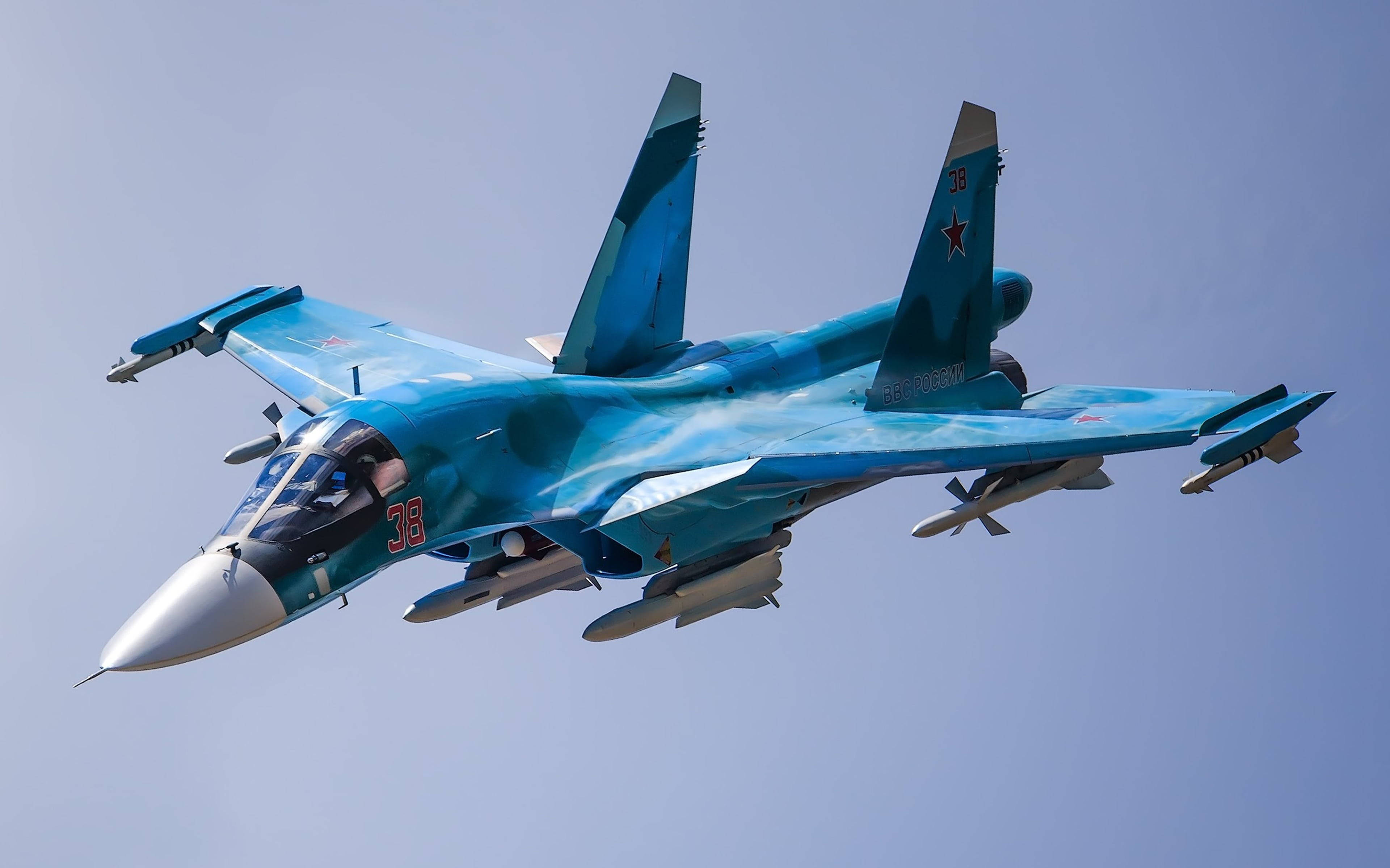 軍事動圖 桌布 壁紙 — 一架流線型藍色迷彩戰鬥機在清澈的淡藍色天空中翱翔，機翼下裝載著武器。