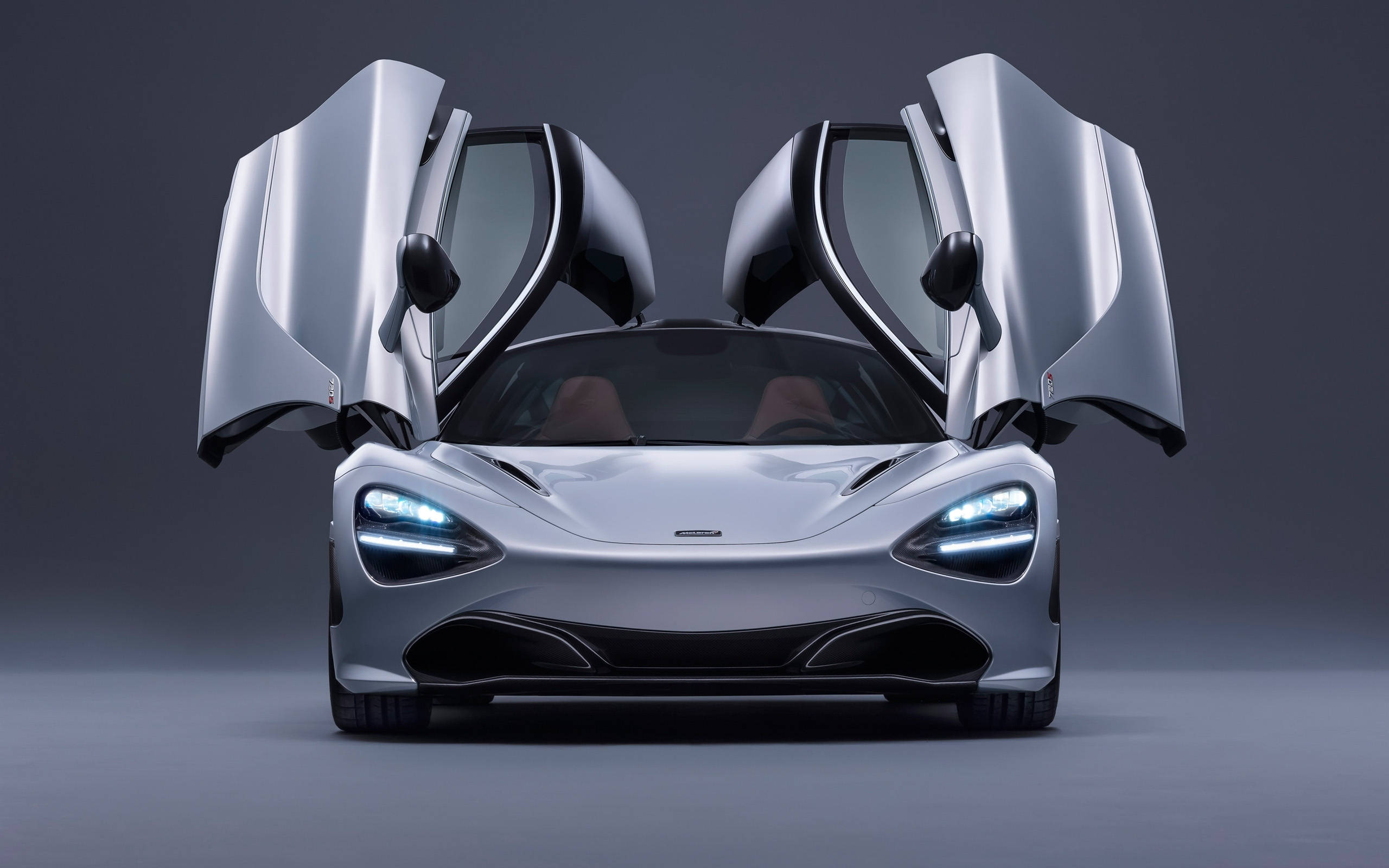 麥拉倫 720S 桌布 壁紙 — 一架流線型銀色McLaren跑車，鷗翼車門打開，以深灰色工作室背景襯托。