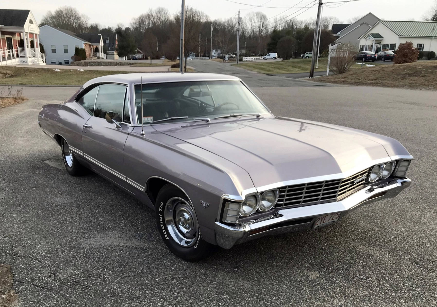 chevrolet impala 1967 桌布 壁紙 — 一架流線型銀色經典肌肉車停泊在寧靜的住宅街道上，背景有房屋和光禿禿的樹木。
