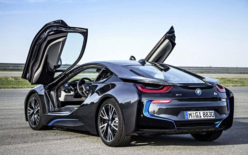 Black Bmw 桌布 壁紙 — 一架流線型黑色BMW i8跑車，在晴朗藍天下於賽道上打開鷗翼車門。