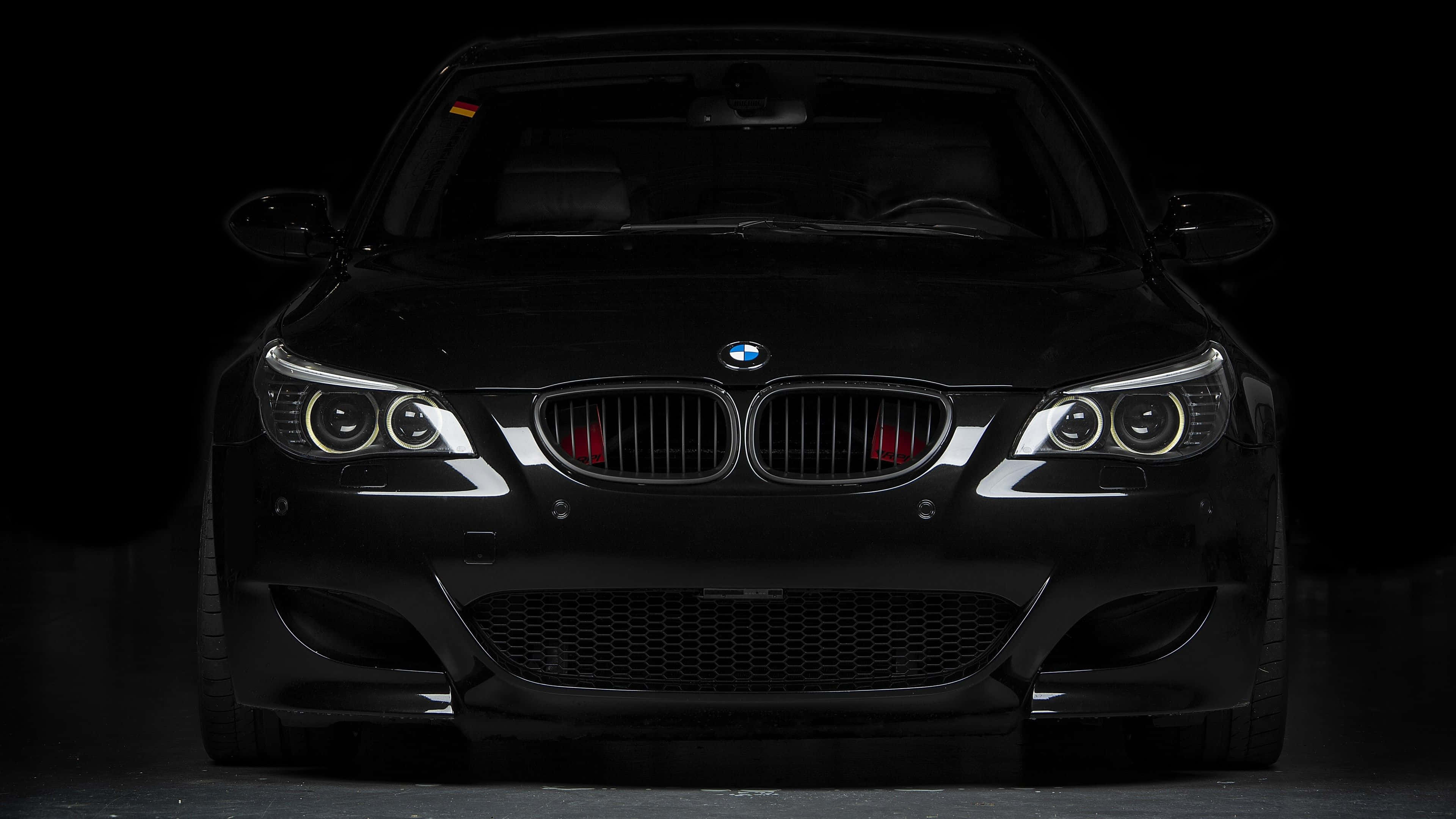 Bmw Tablet 桌布 壁紙 — 一架流線型黑色BMW跑車在漆黑的工作室背景中亮起車頭燈。