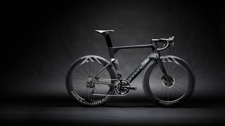 桌布 壁紙 — 一架流線型黑色Cannondale公路自行車配備深截面車輪，在黑暗的攝影棚背景下戲劇性地照亮。