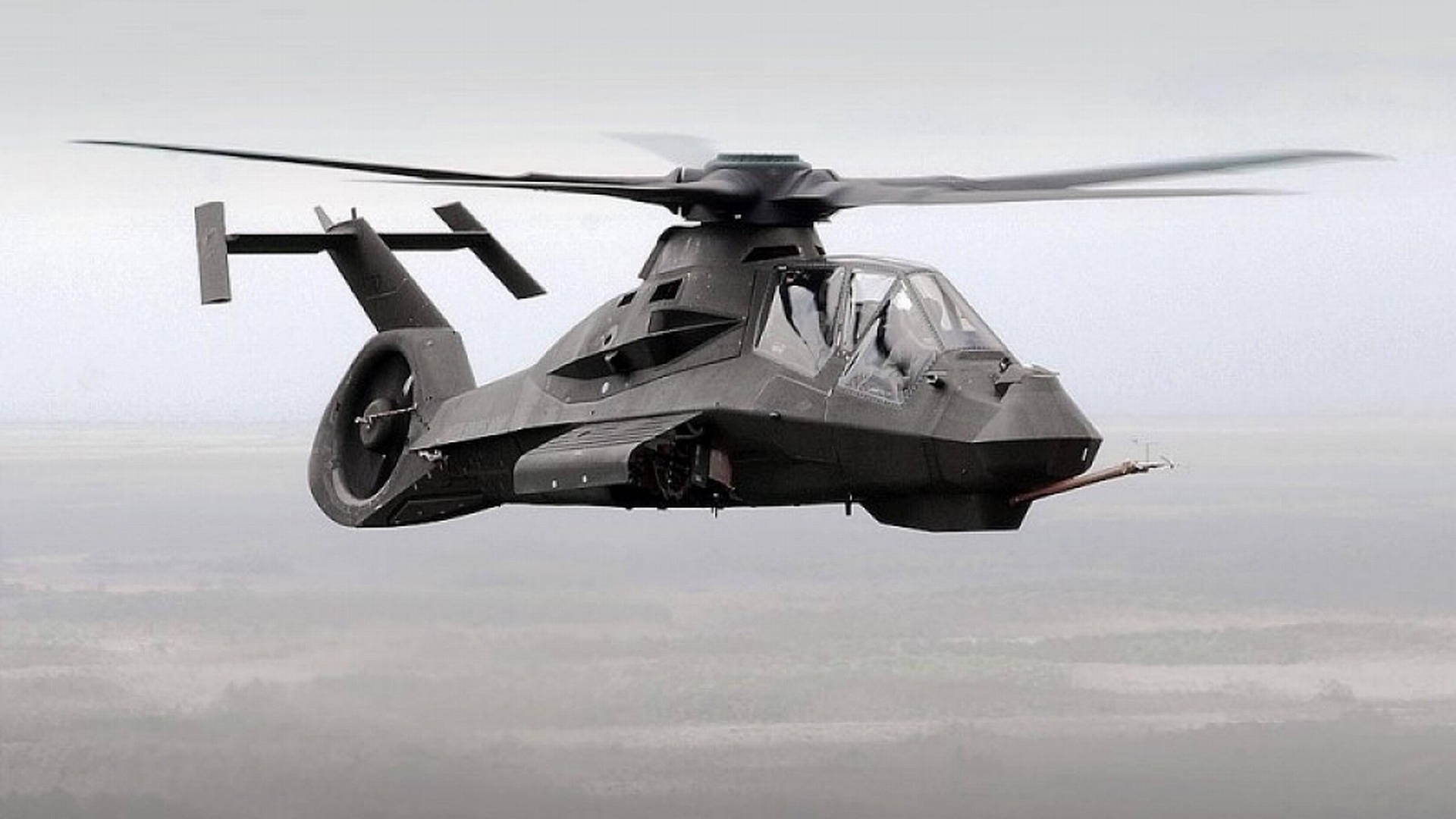 Helicopter 桌布 壁紙 — 一架流線型黑色隱形直升機低空盤旋於霧氣瀰漫、地形模糊的景觀之上。