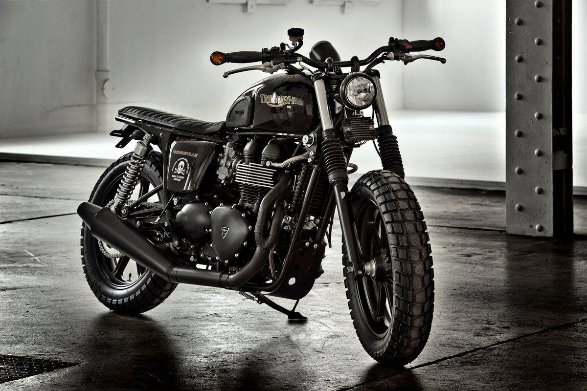 Triumph 桌布 壁紙 — 一架消光黑色的 Triumph Bonneville Bobber 摩托車矗立在一個簡樸的工業倉庫中，地面是混凝土，鋼樑用鉚釘固定。
